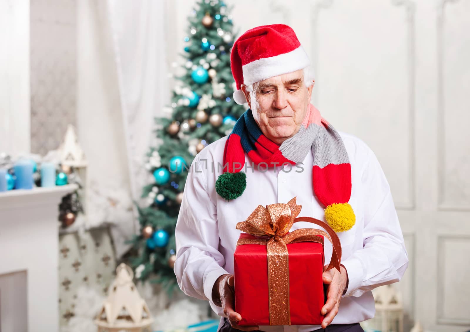 Senior man holding a red gift box on Christmas background