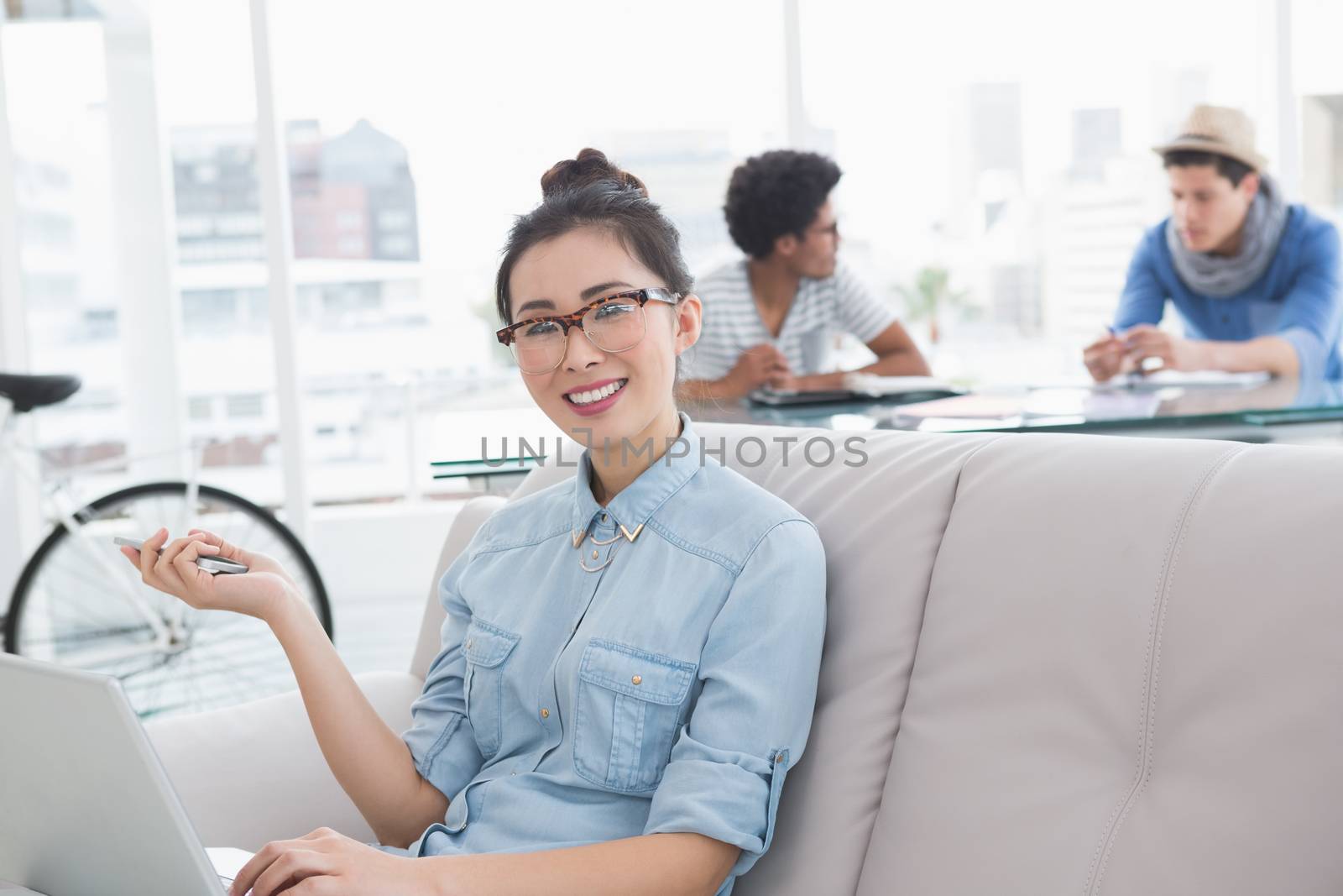 Young creative woman using laptop on couch in creative office