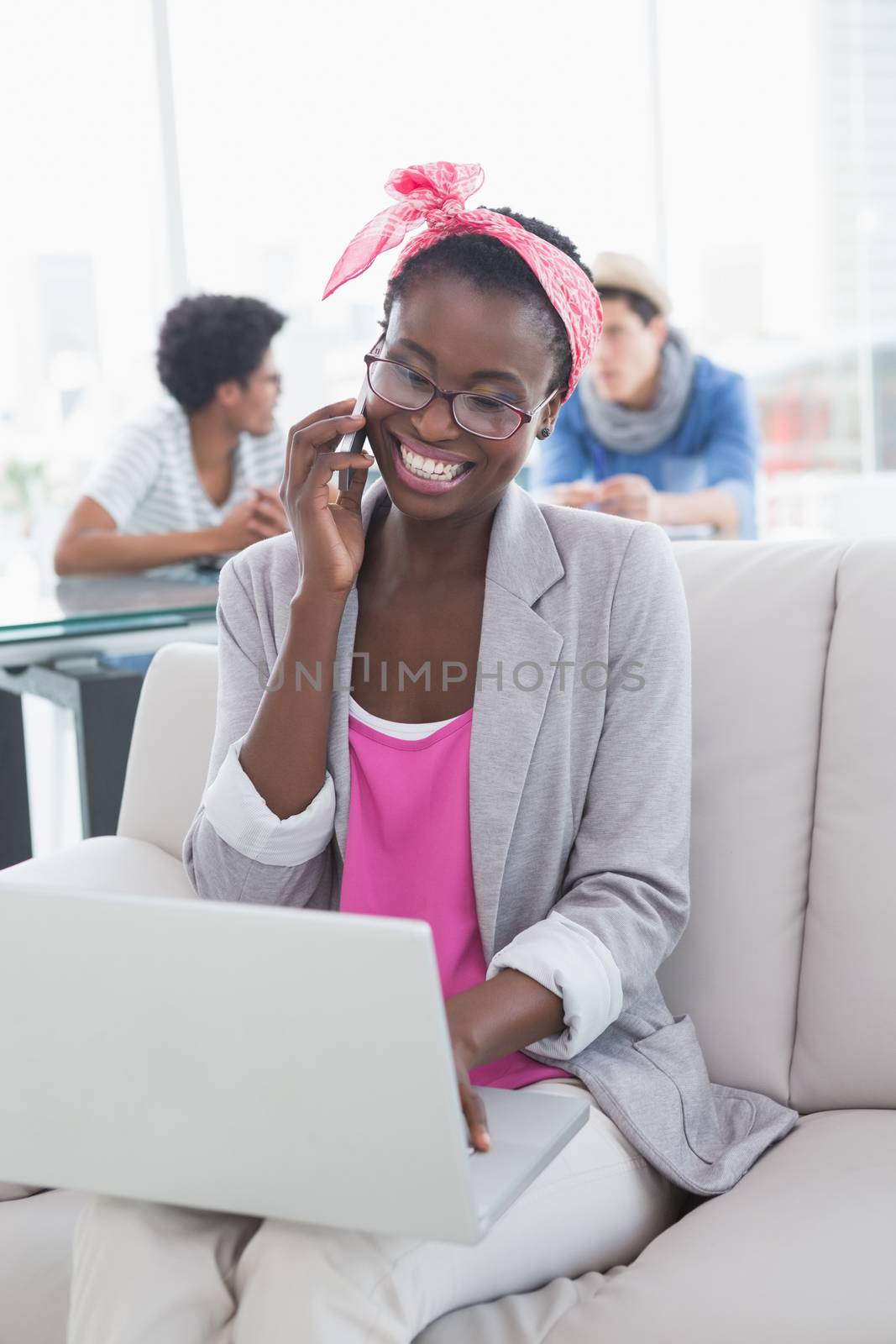 Young creative woman using laptop on couch in creative office