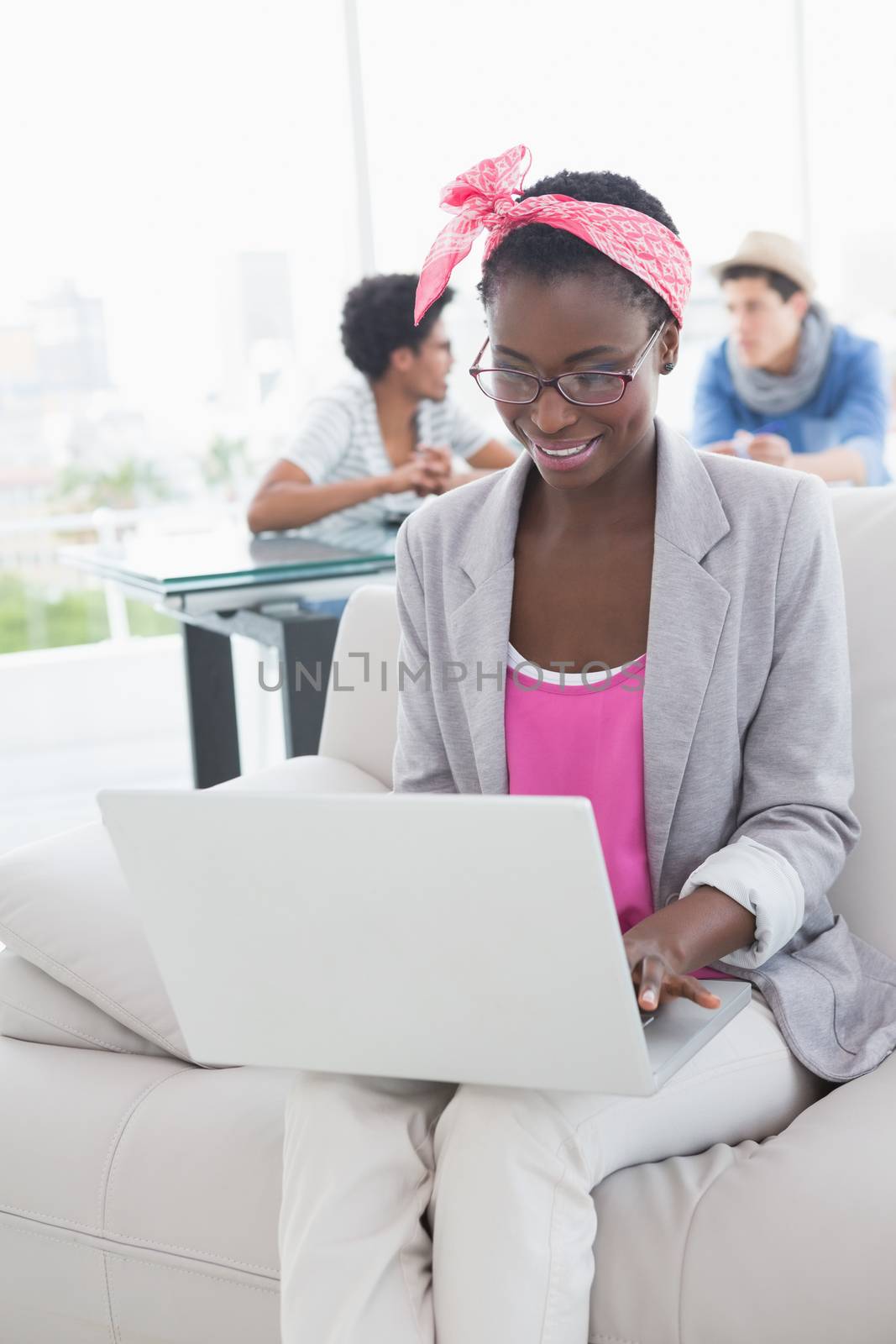 Young creative woman using laptop on couch in creative office