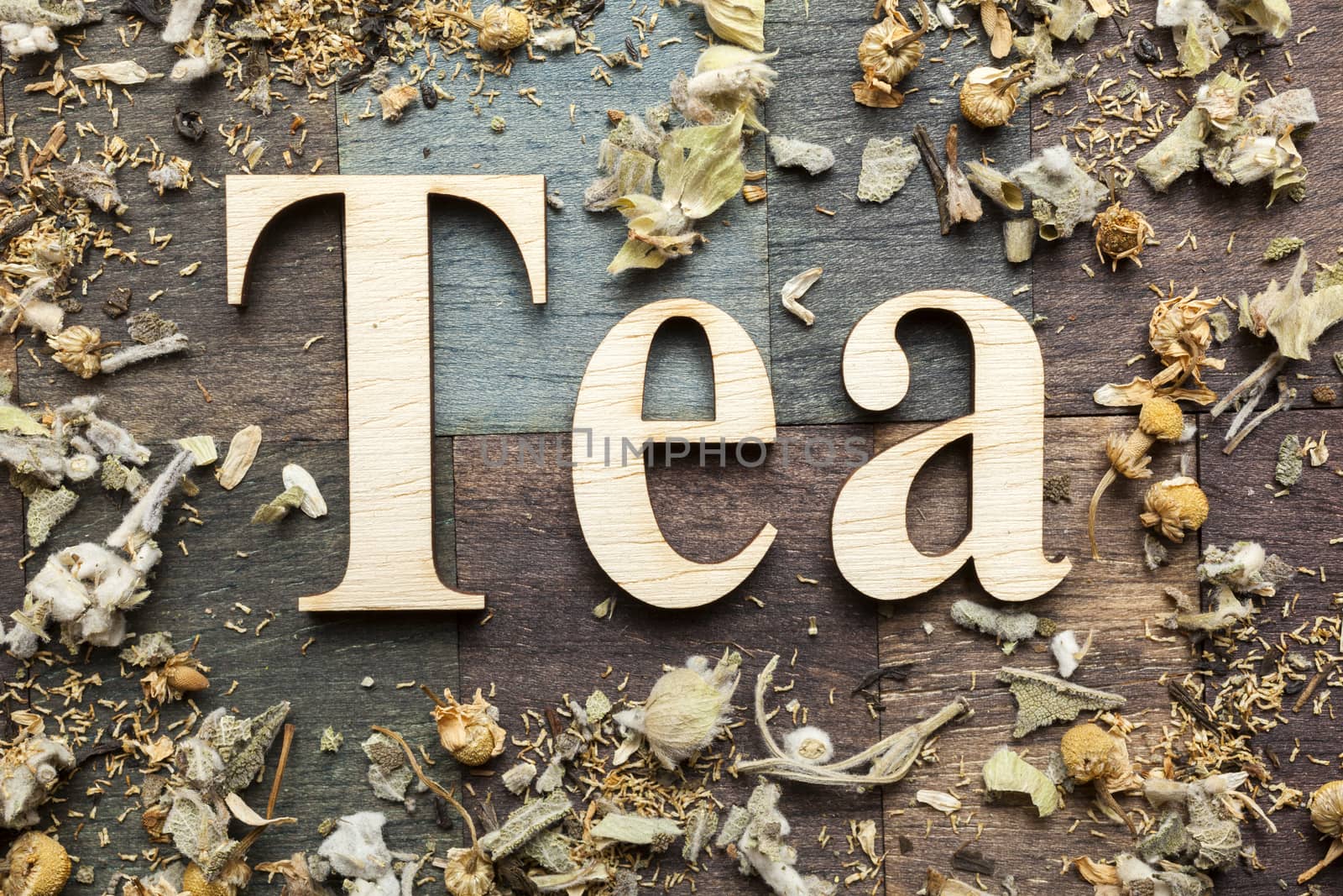 Tea time words and dry mountain tea leaves on wooden background