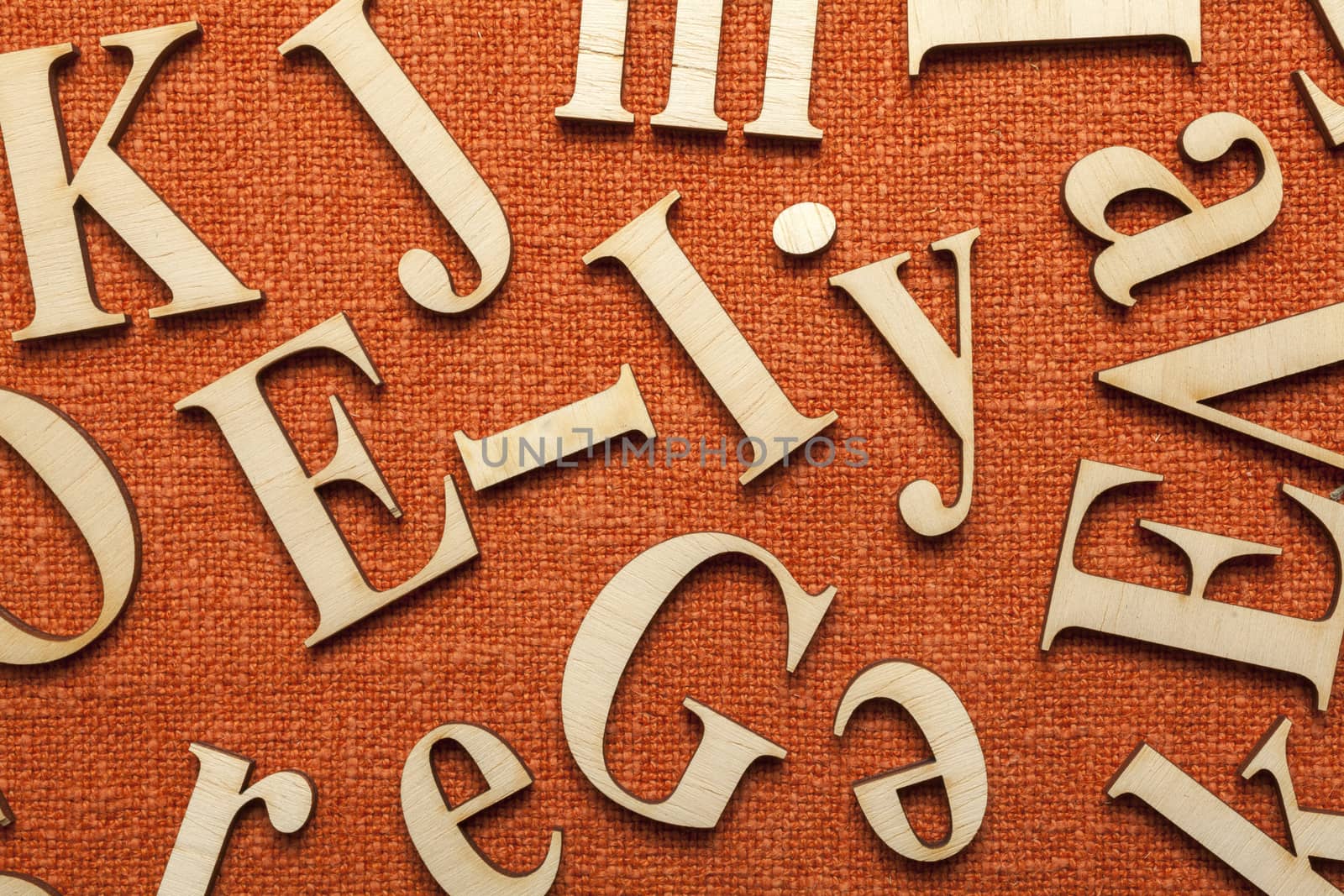 Wooden alphabet letters on orange fabric surface with space for your own text.