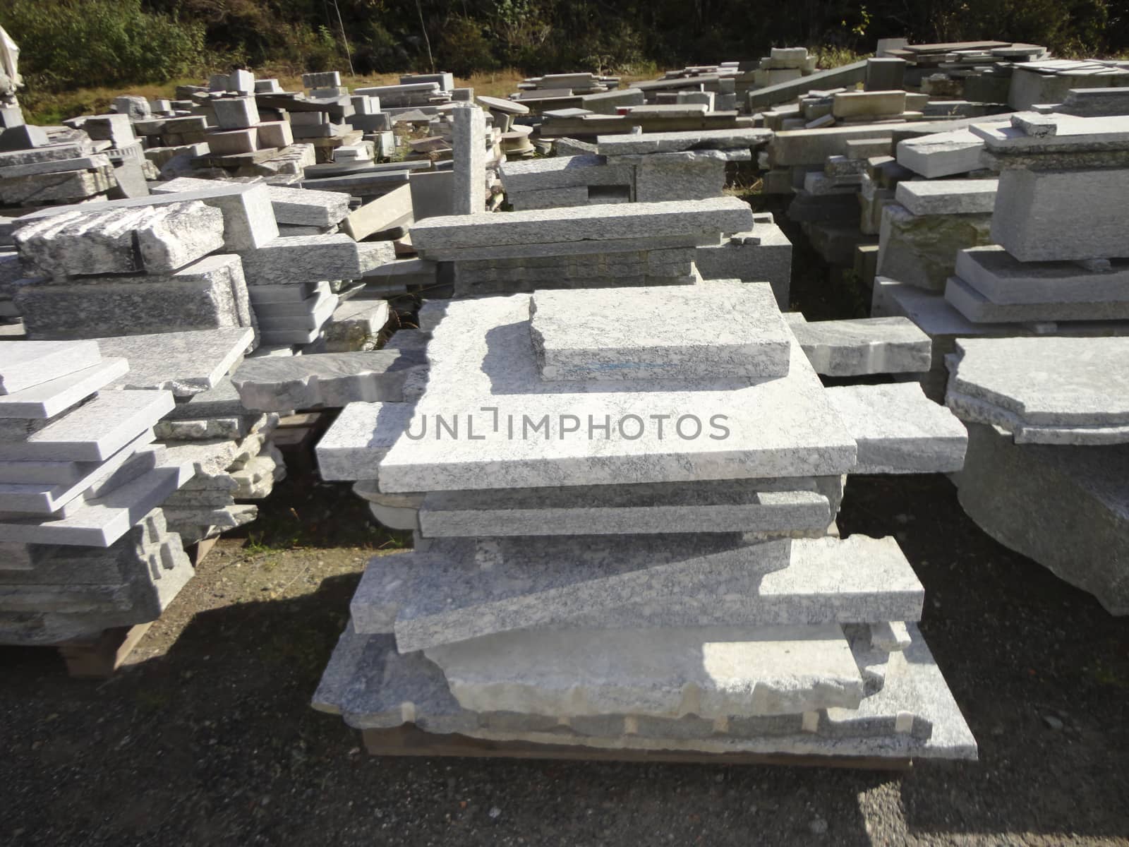 Stacks of granite slabs in a yard under sunlight by madfoto