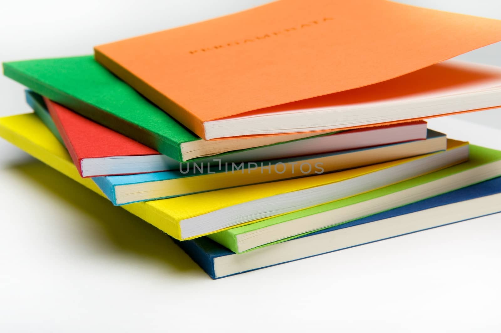 Horizontal shot of seven vibrantly colored workbooks isolated on the white background