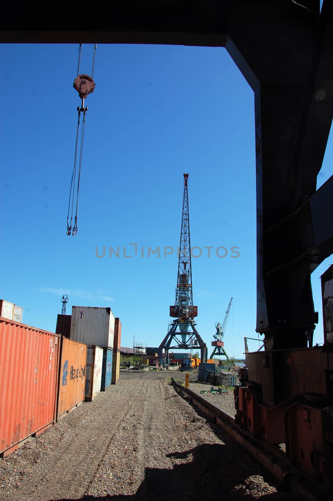 Crane loading metal container to ship at Kolyma river port, Russia