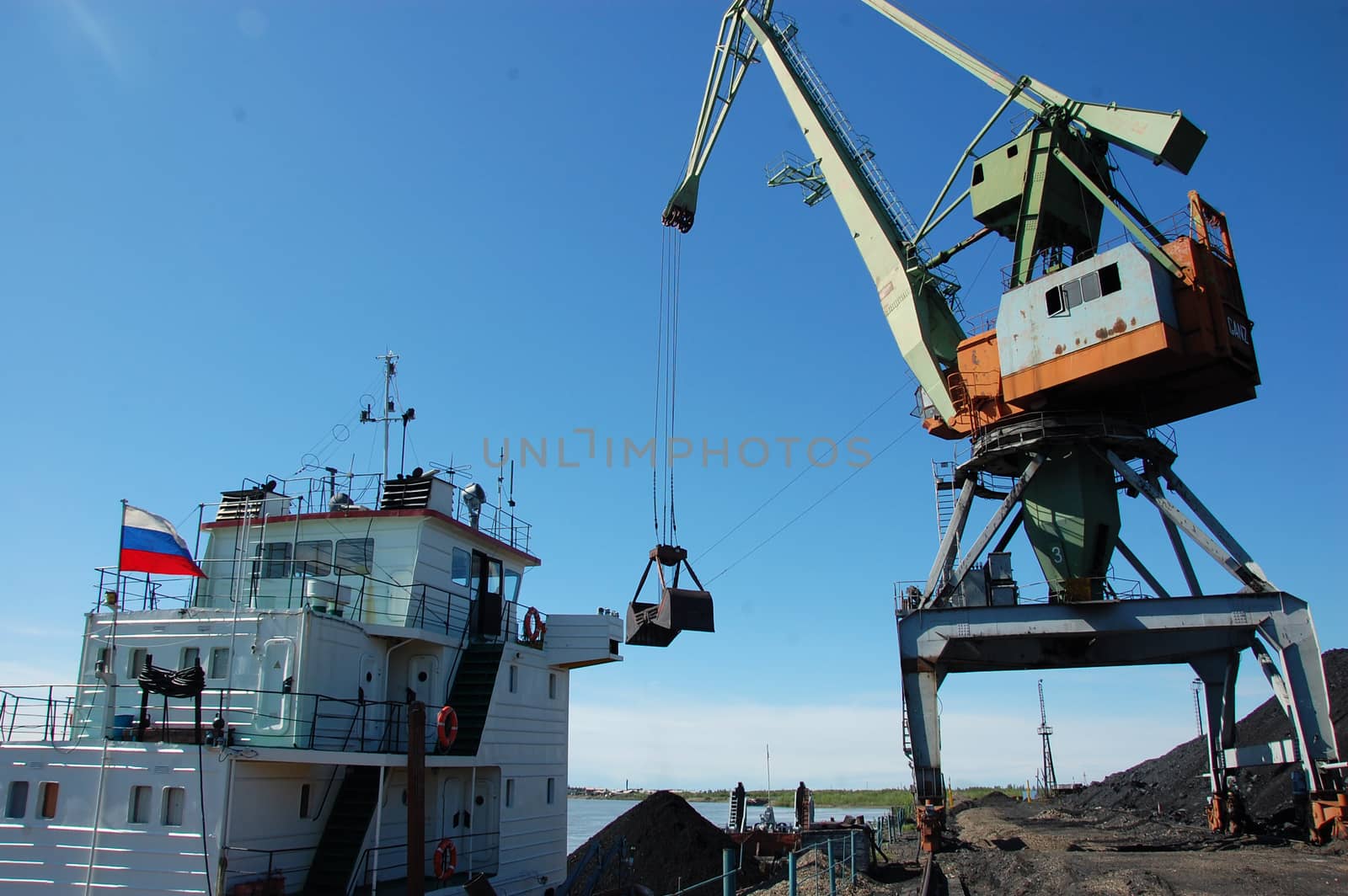 Crane loading coal to ship at Kolyma river port, Russia