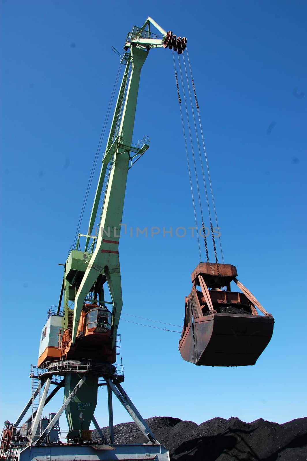 Crane loading coal to ship at Kolyma river port by danemo