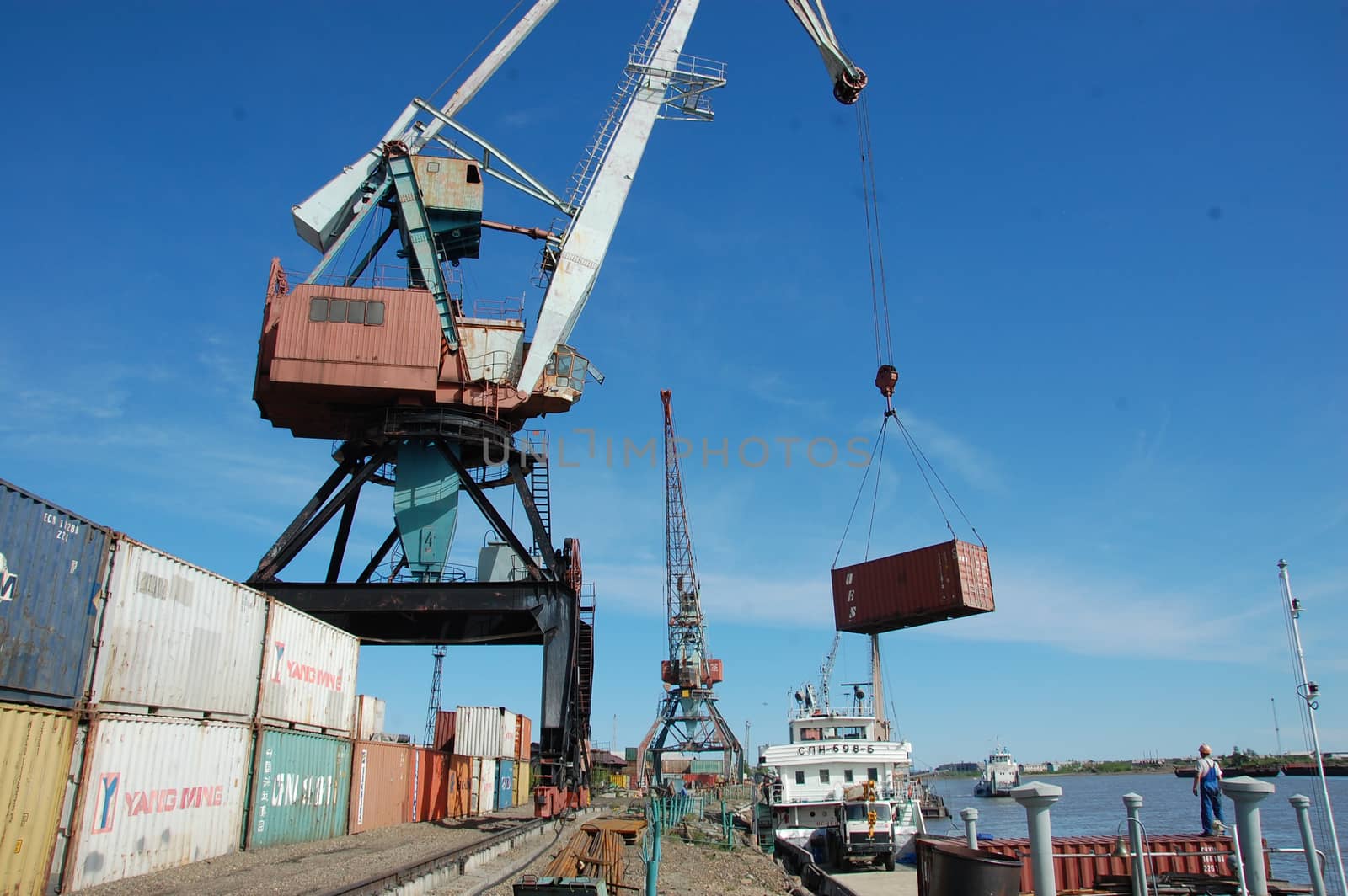 Crane loading metal container to ship at Kolyma river port by danemo