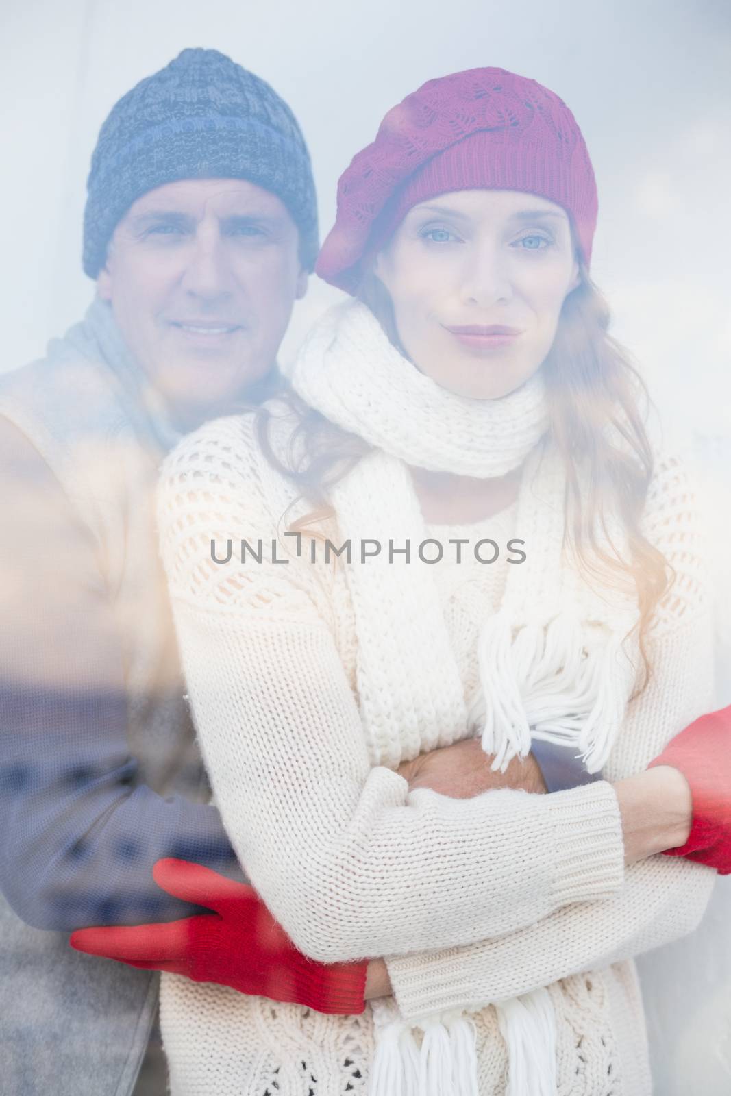 Happy couple in warm clothing seen through glass window