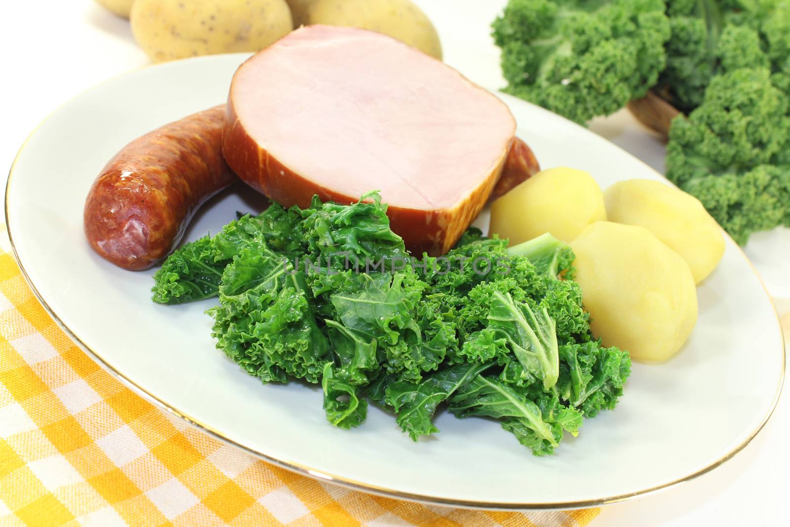 a white plate with kale, smoked meat and pee sausage