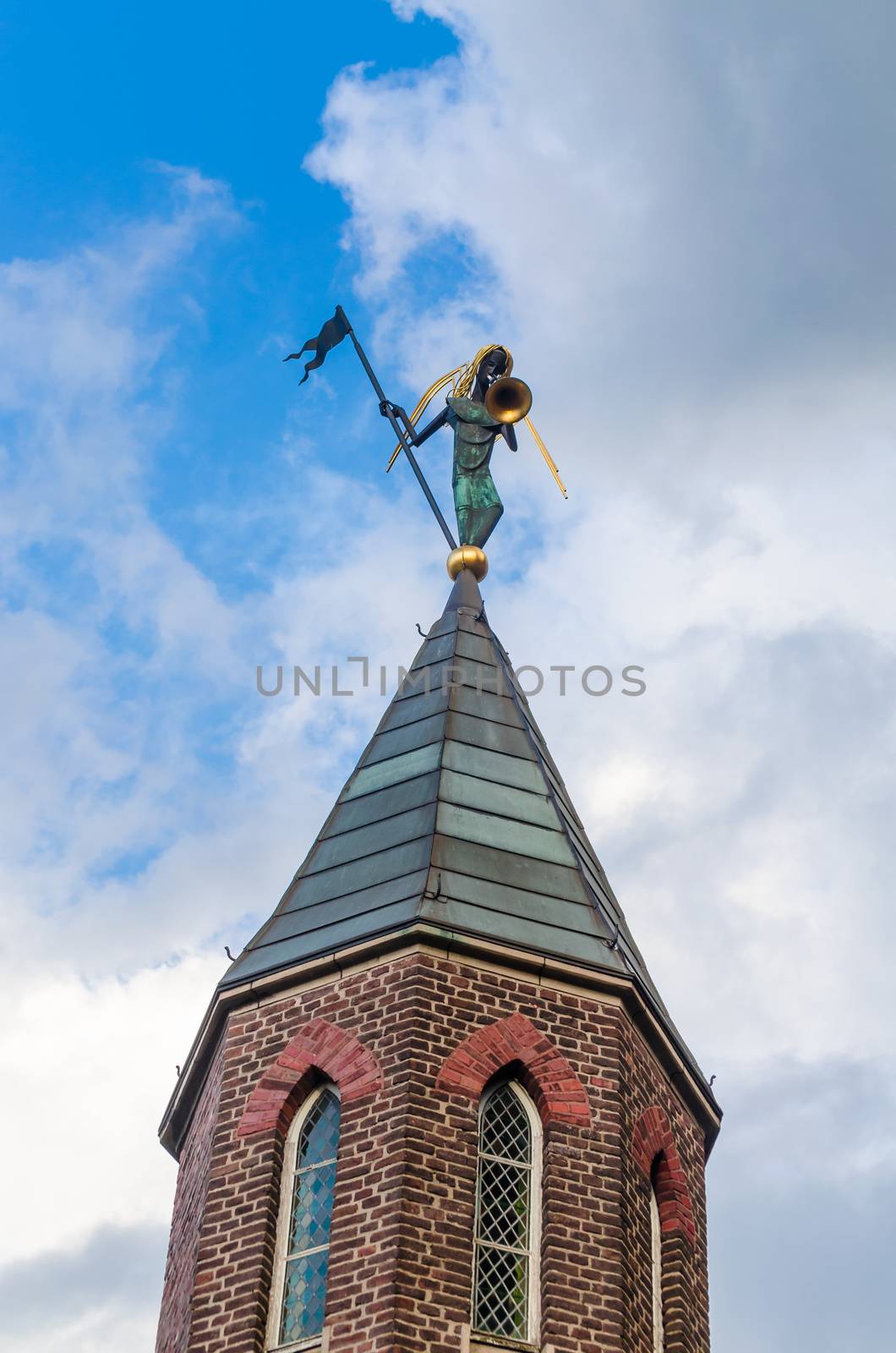 Church spire with trombonist before blue sky