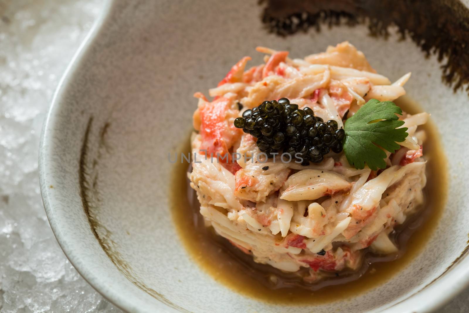 Crab meat in a dish on wood table with black caviar
