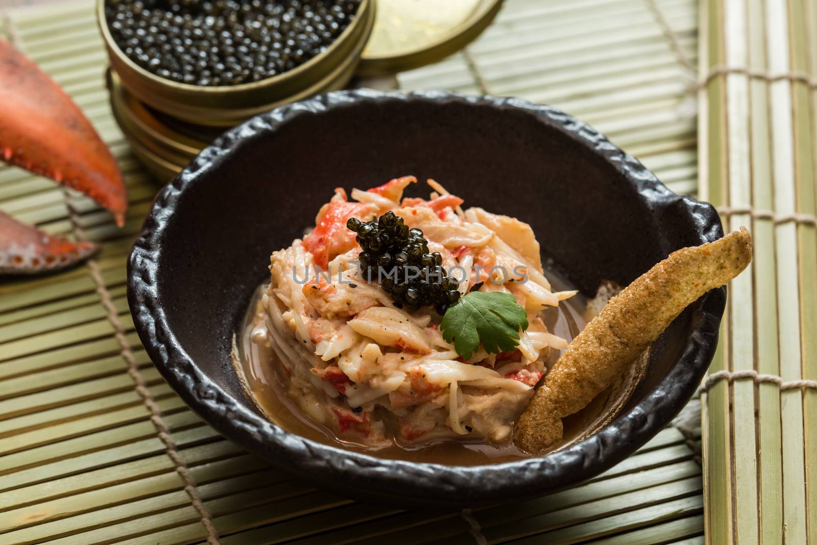 Crab meat in a dish on wood table with black caviar