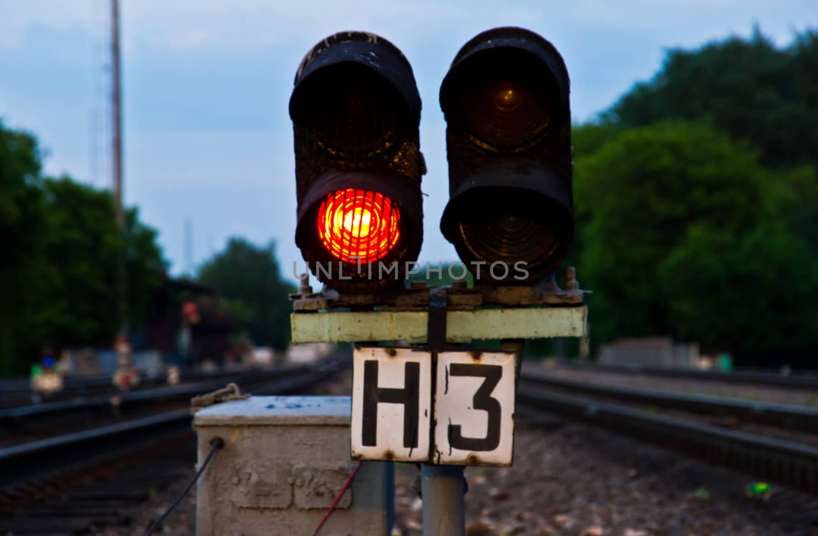 Railway traffic light on the background of green trees