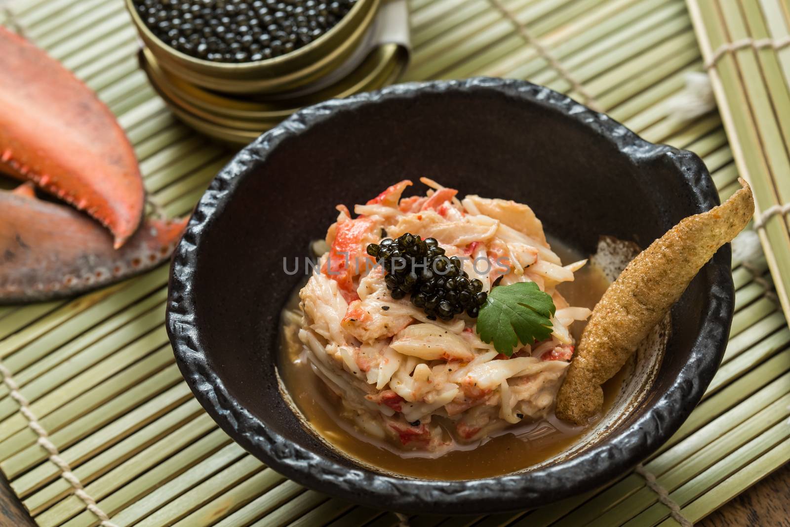 Crab meat in a dish on wood table with black caviar