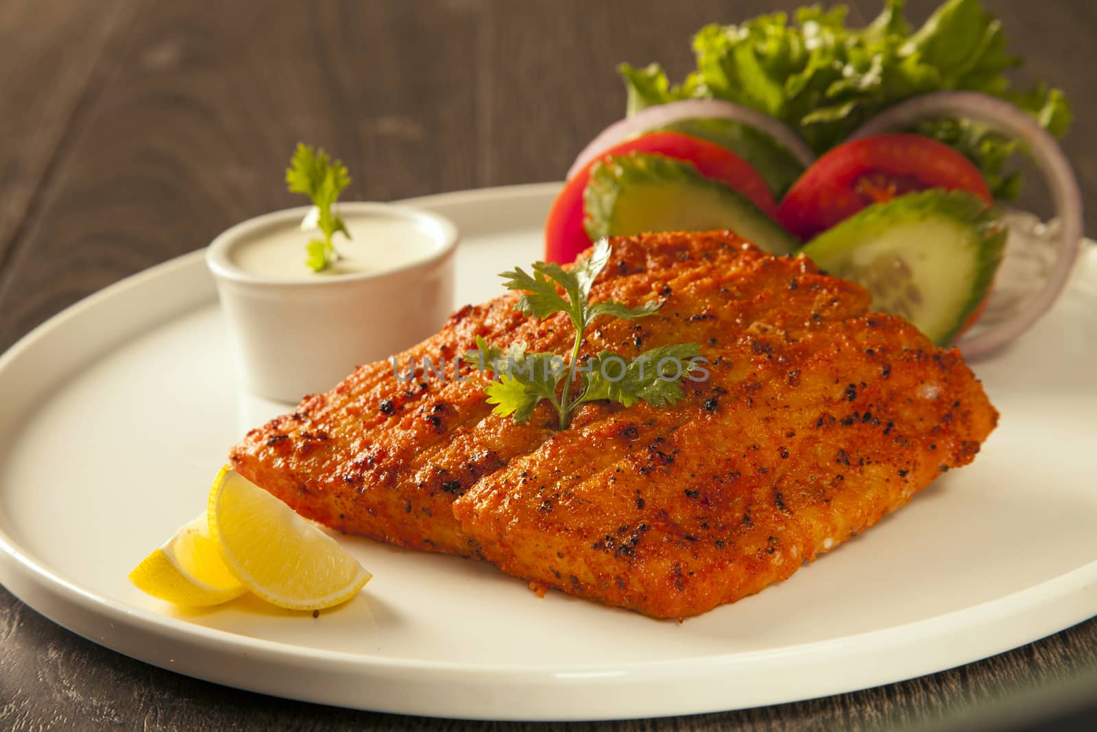 Grilled fish tikka served on a plate with salad and tarter sauce by haiderazim