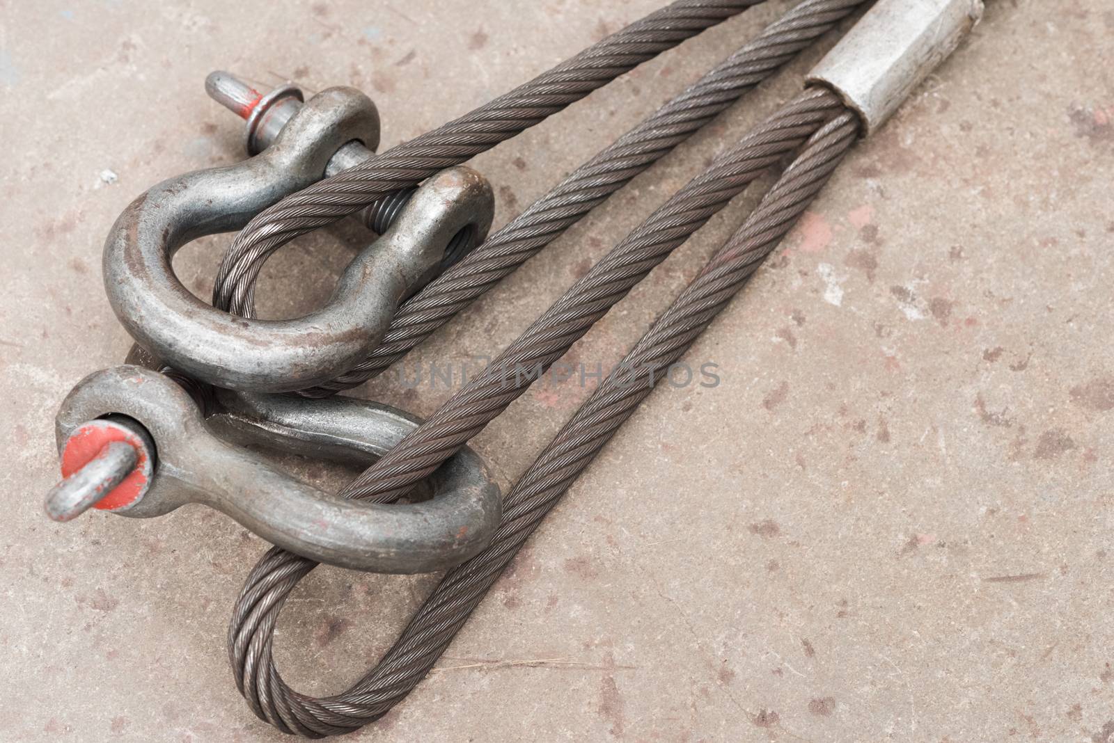 Two used steel wire loops on a concrete floor with one shackle through each.