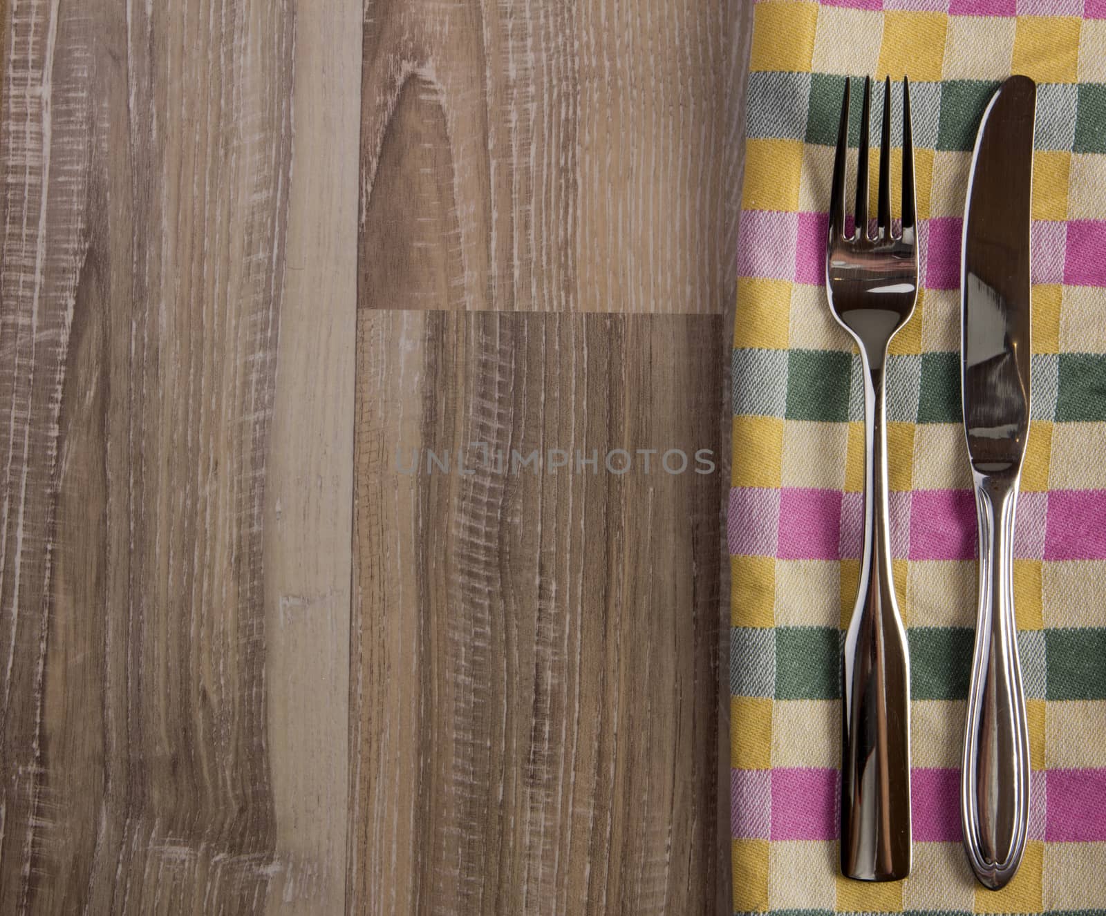 Dishtowel plaid with fork and knife on a rustic wooden background 