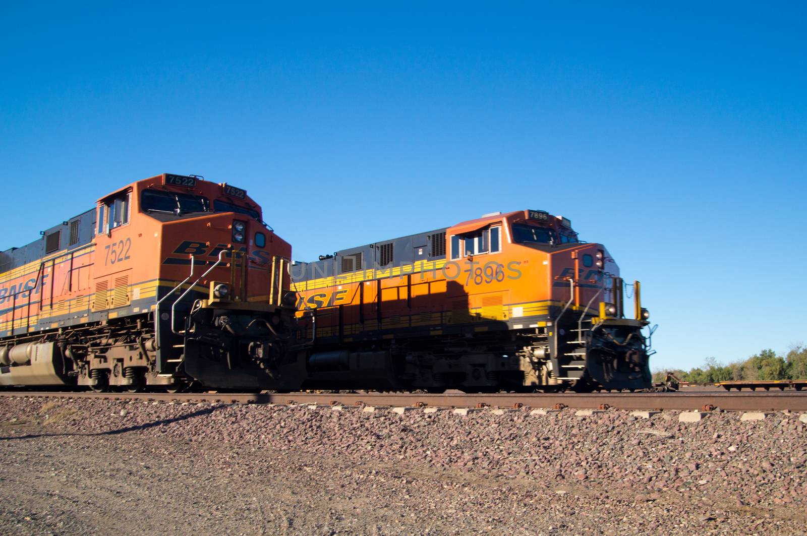 Distinctive orange and yellow Burlington Northern Santa Fe Locomotive freight trains No. 7522 and 7896 on the tracks at the town of Needles, California. Photo taken in February 2013.