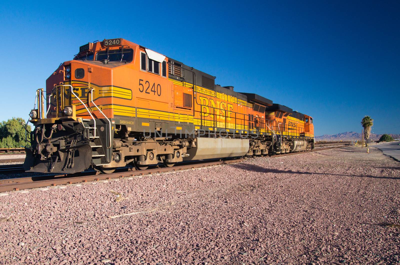 Distinctive orange and yellow Burlington Northern Santa Fe Locomotive freight train No. 5240 on the tracks at the town of Needles, California. Photo taken in February 2013.