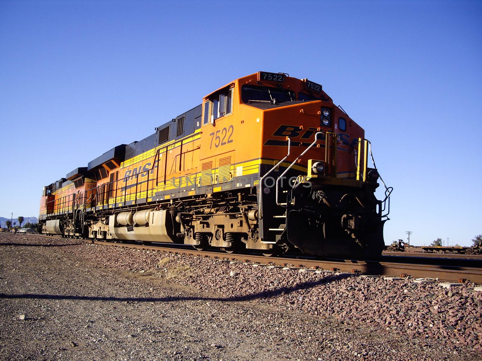 Distinctive orange and yellow Burlington Northern Santa Fe Locomotive freight train No. 7522 on the tracks at the town of Needles, California. Photo taken in February 2013.