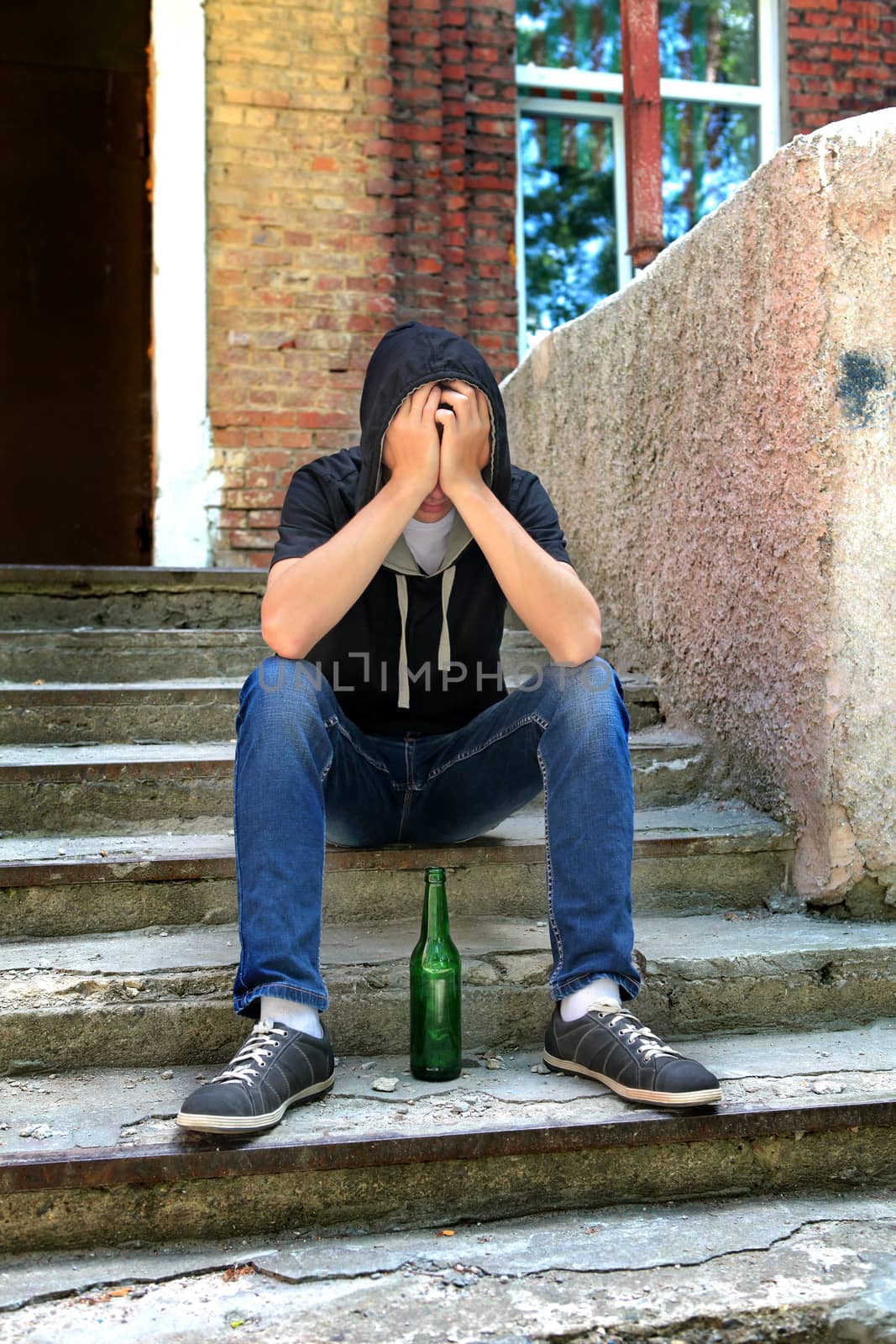 Sad Teenager on the landing steps with a Bottle of the Beer