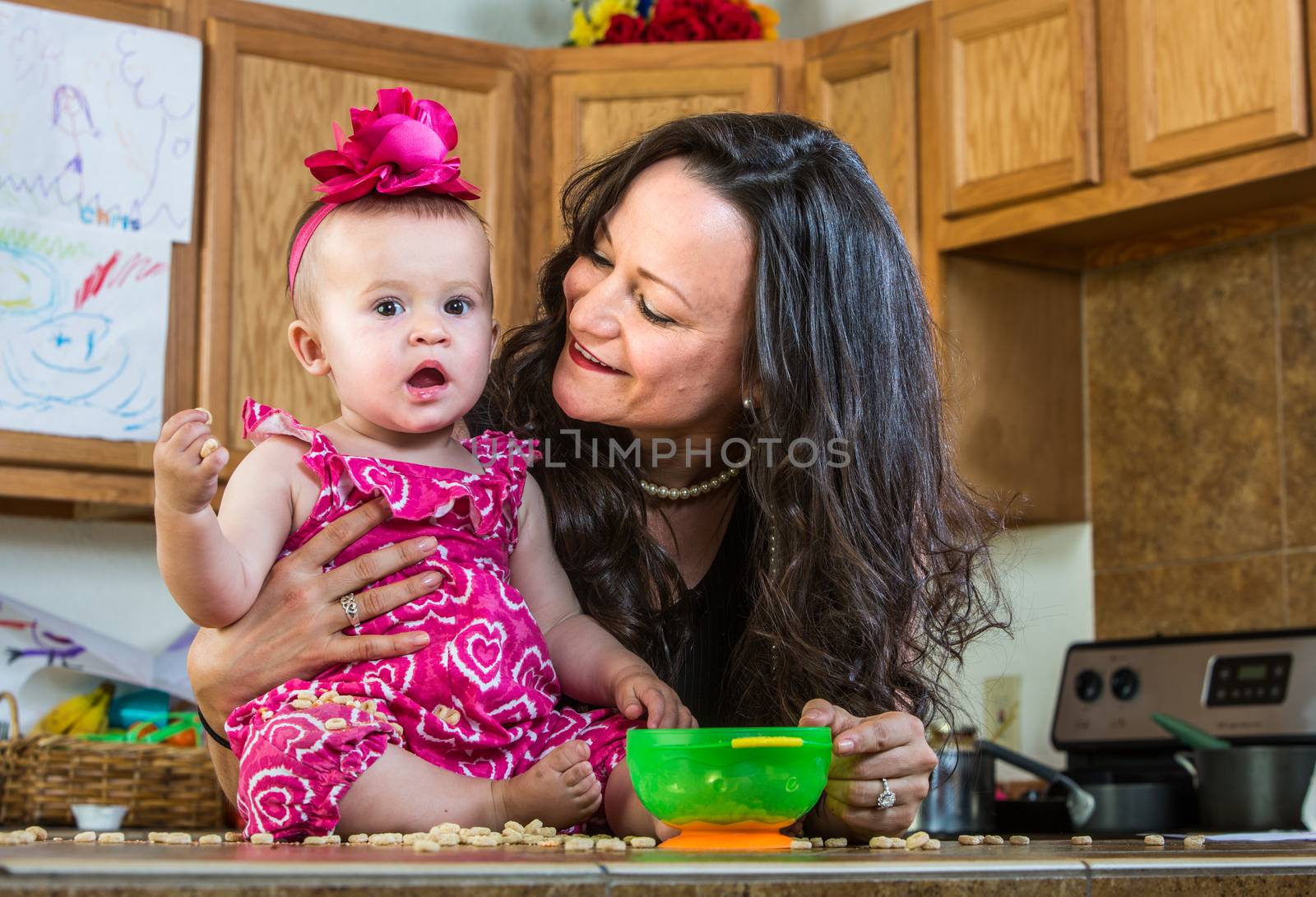 A mother in her kitchen smiles at her baby