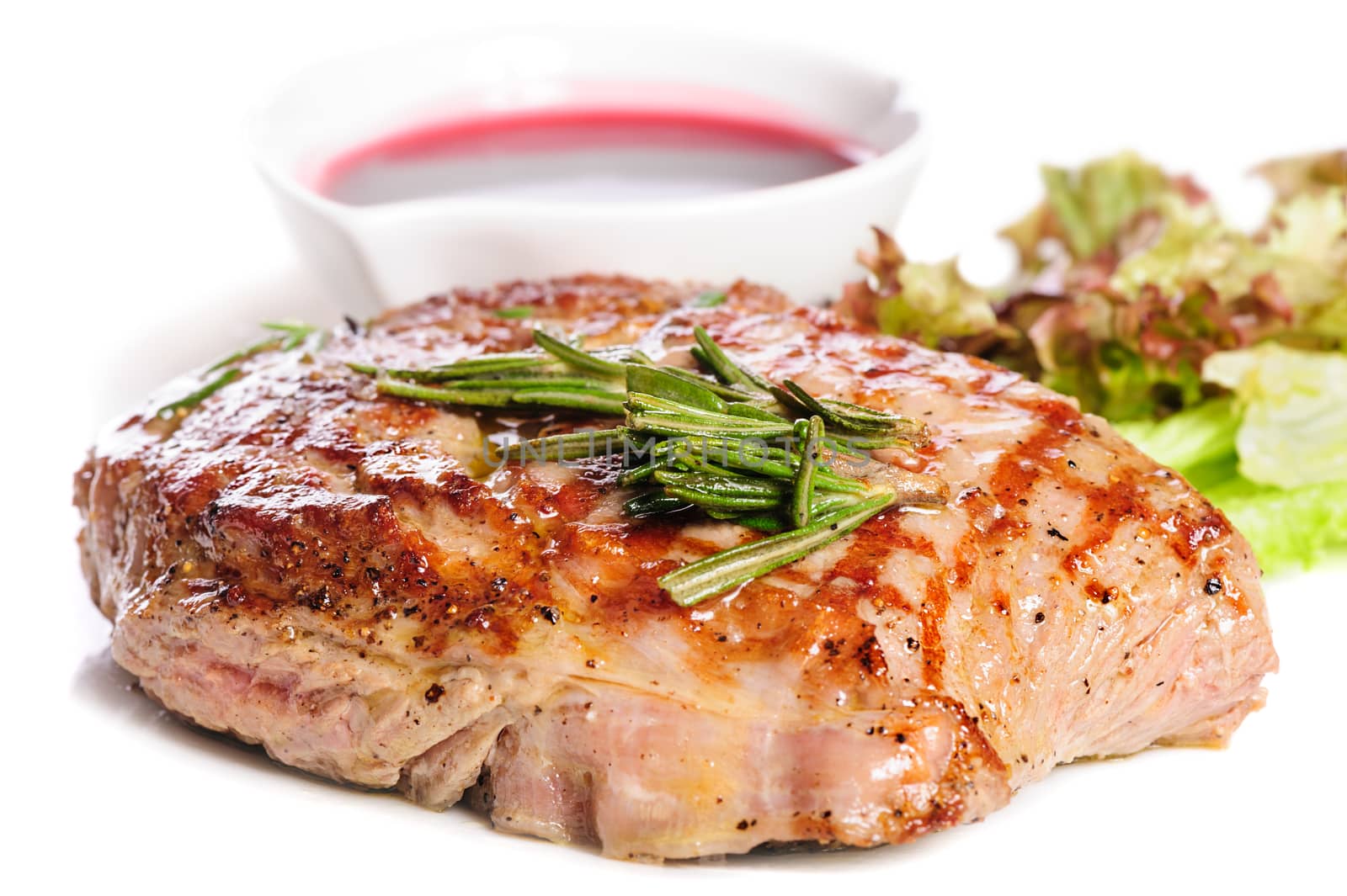 Grilled pork steaks with raspberry sauce, rosemary and leaf of lettuce