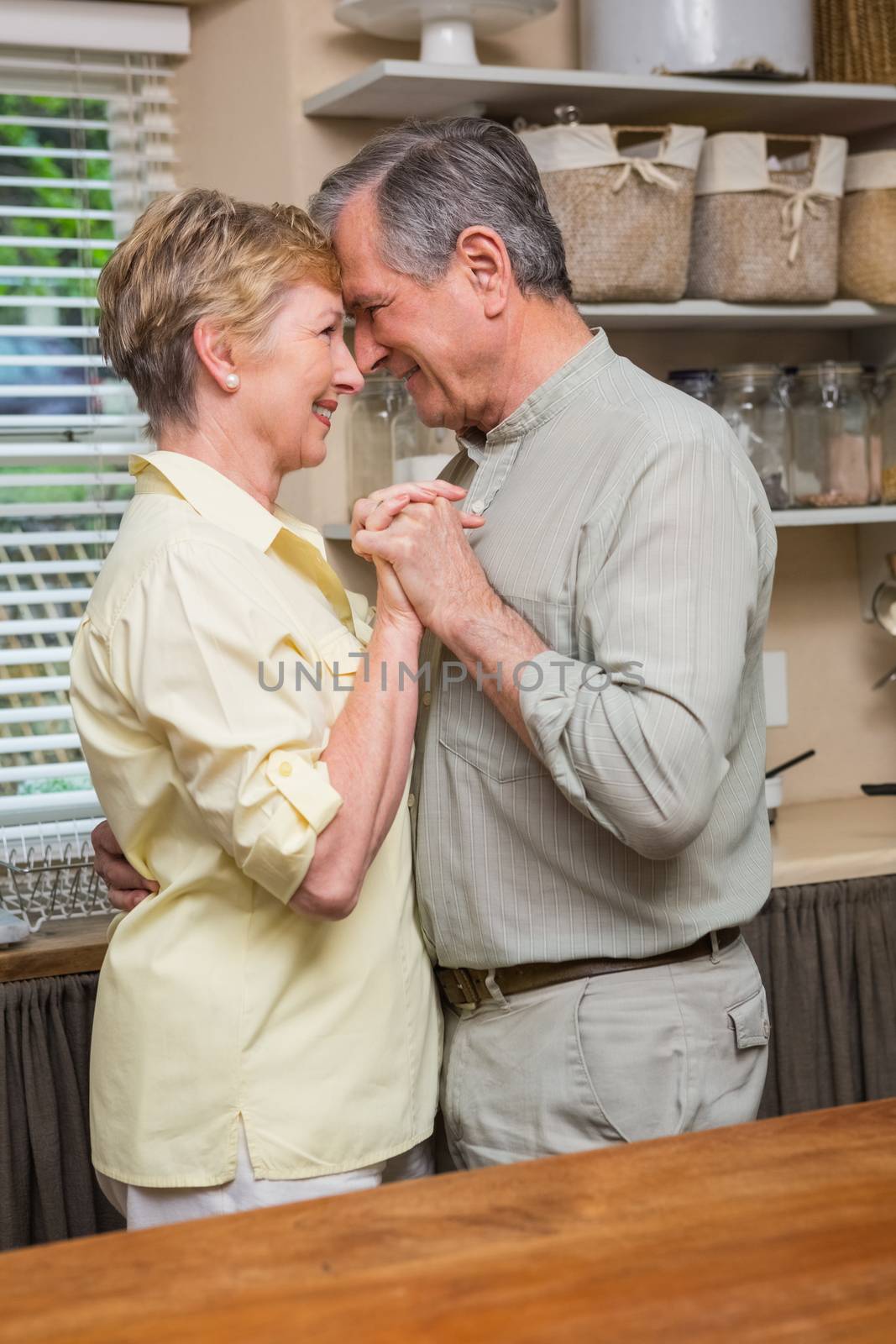 Romantic senior couple dancing together  at home in the kitchen