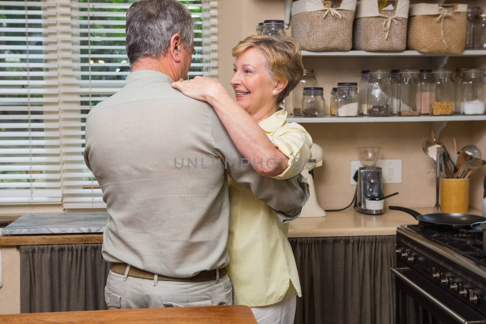 Romantic senior couple dancing together  at home in the kitchen