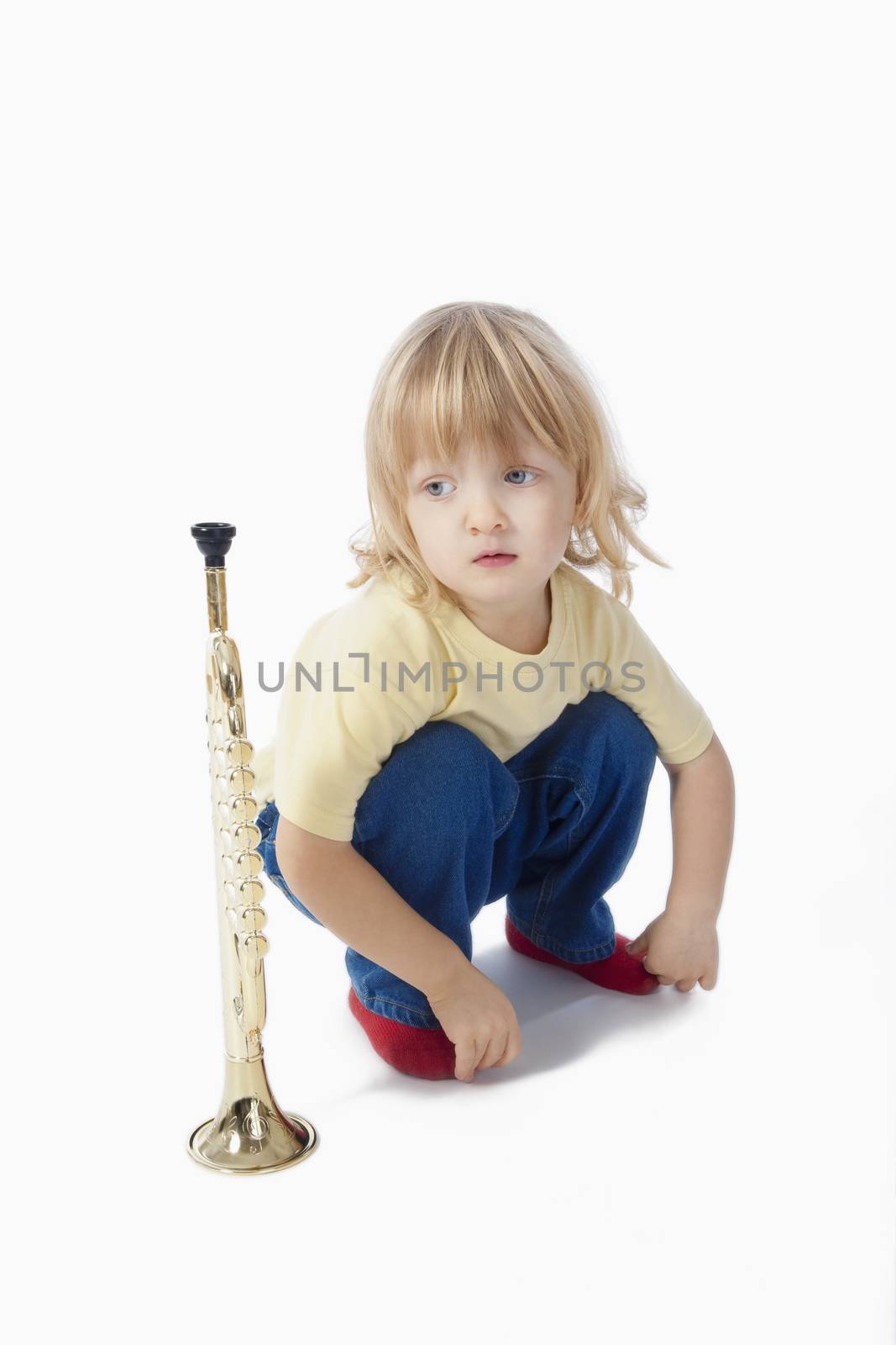 boy with long blond hair playing with toy trumpet