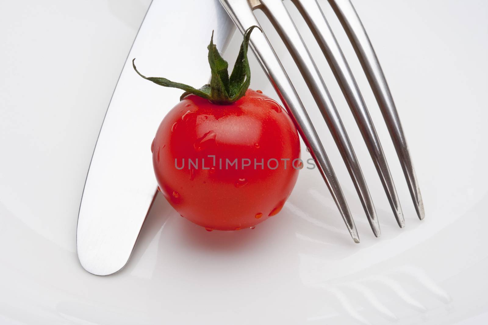 closeup of cherry tomatoes with fork and knife isolated on white