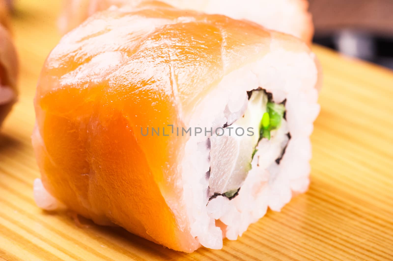 sushi roll set covered in salmon on wooden background 