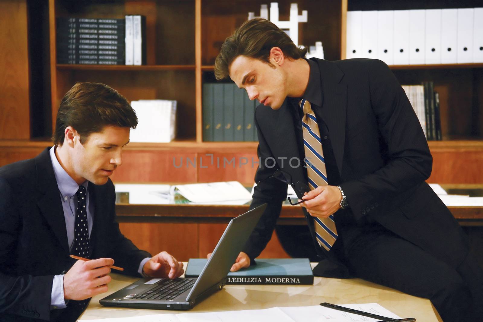 Business meeting - two businessmen in suits working together in boardroom