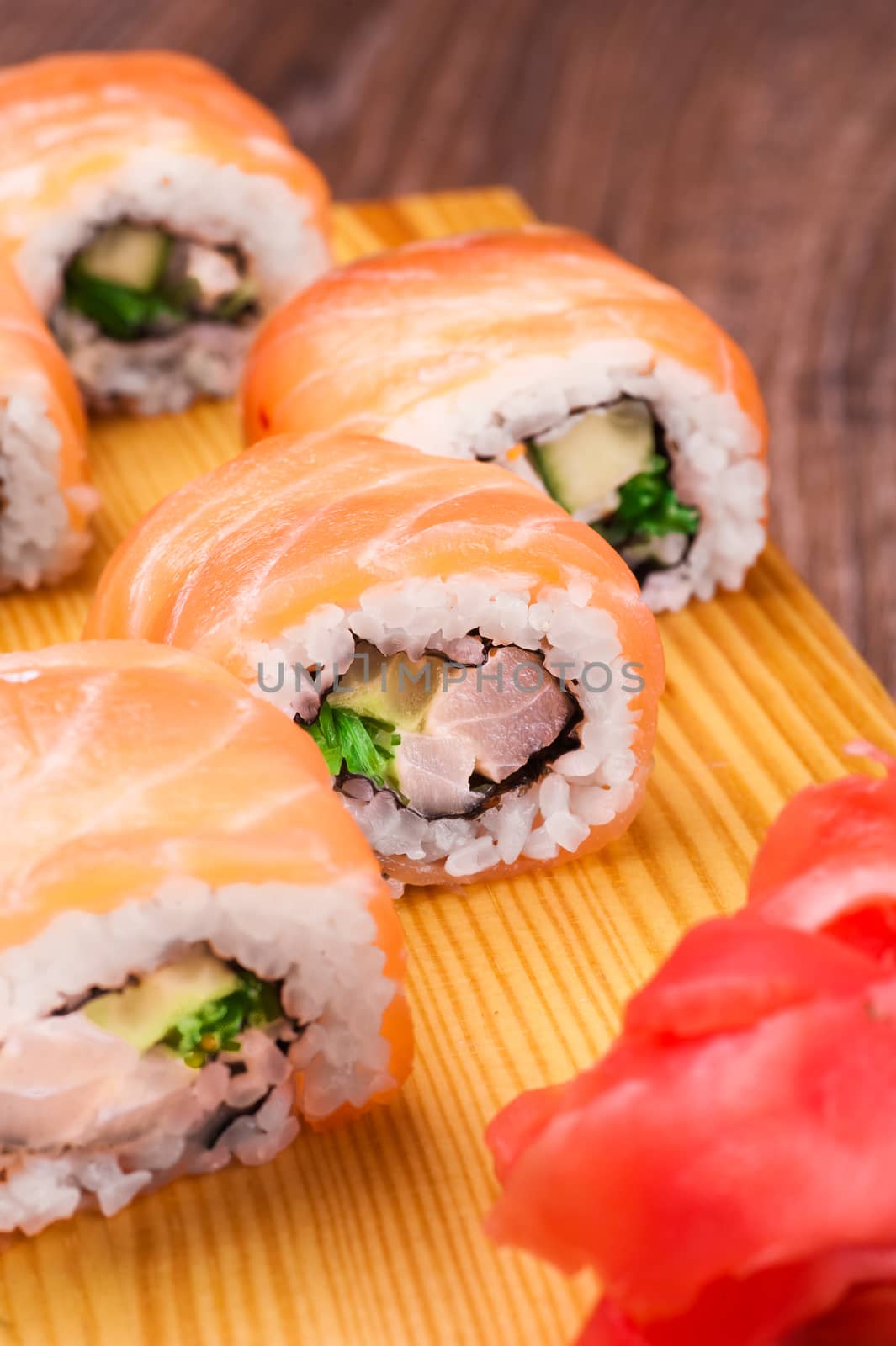 sushi roll set covered in salmon on wooden background 