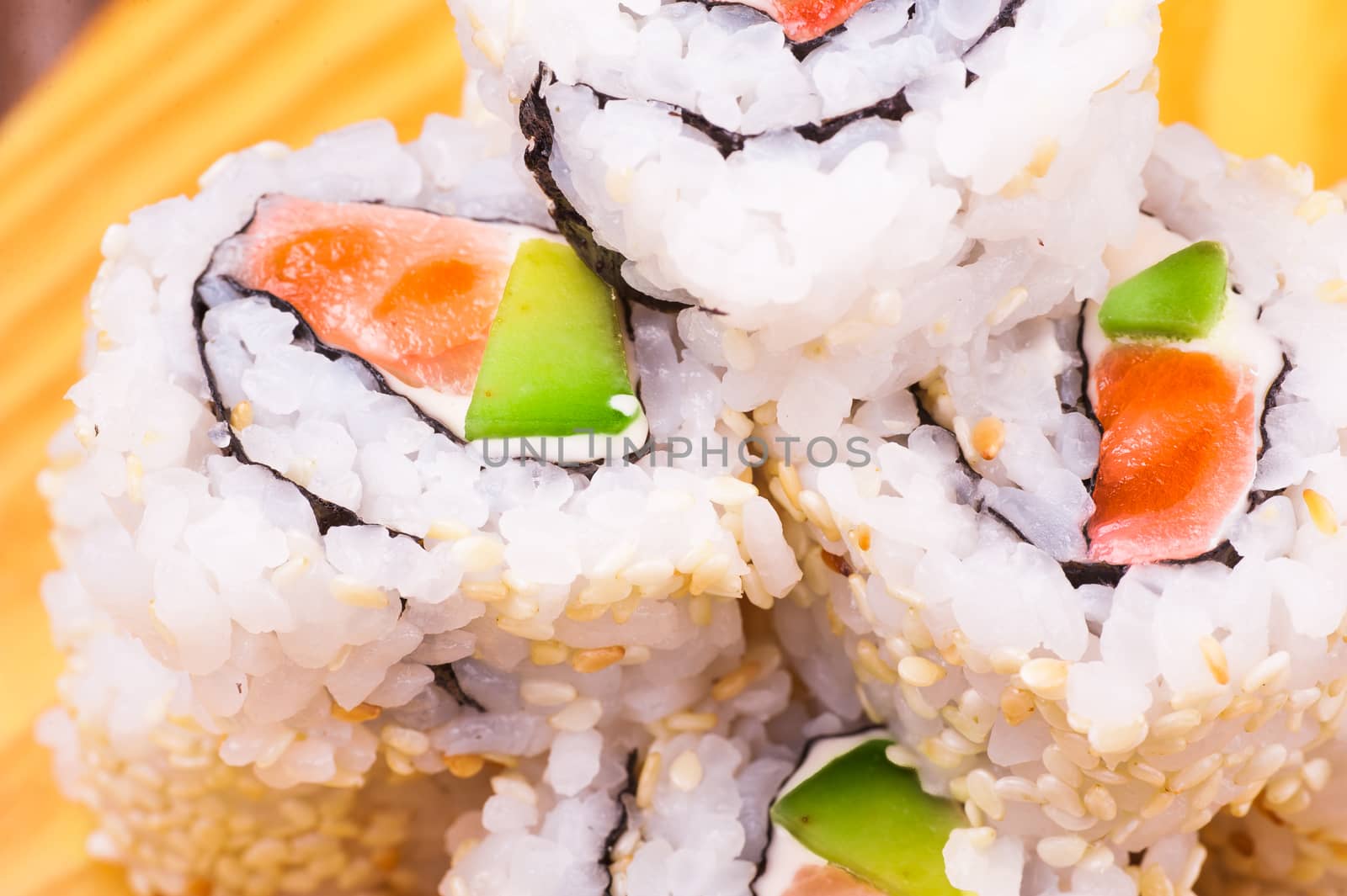 inside out sushi roll with salmon and avocado on wooden background 