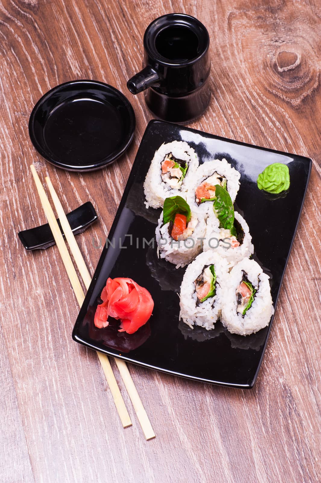 spicy sushi roll set   with ginger, soy sauce, towel and chopsticks n wooden background