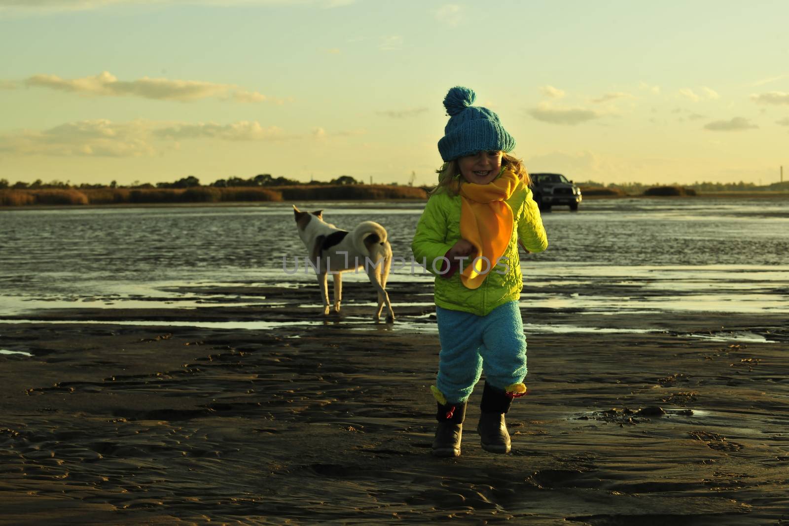 Running  little girl  on a sunset sandy autumn beach. Decline on the coast of the Ladoga Lake
