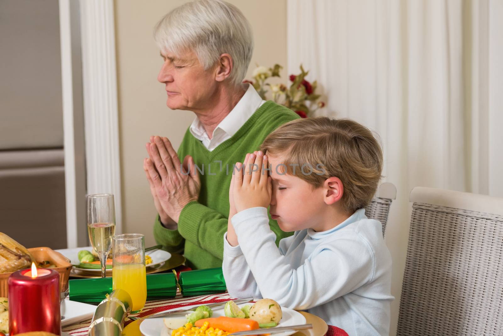 Extended family praying before christmas dinner by Wavebreakmedia