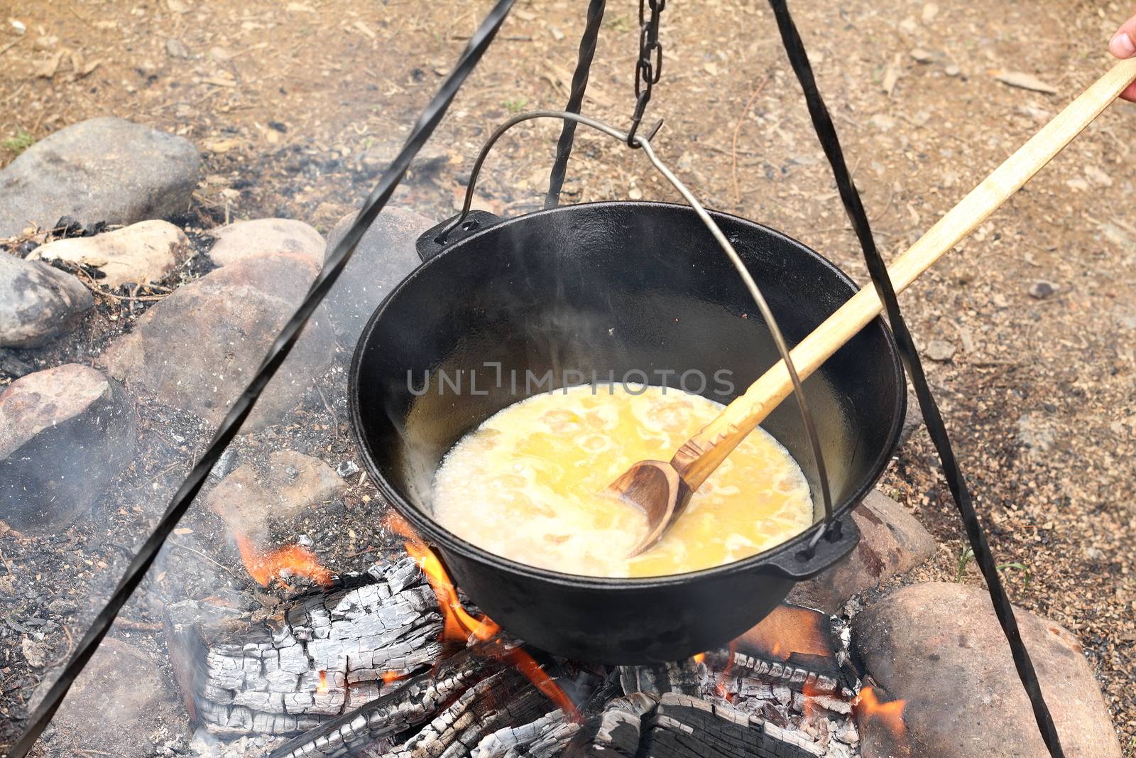 cooking in a black cauldron on camping fire, slow food