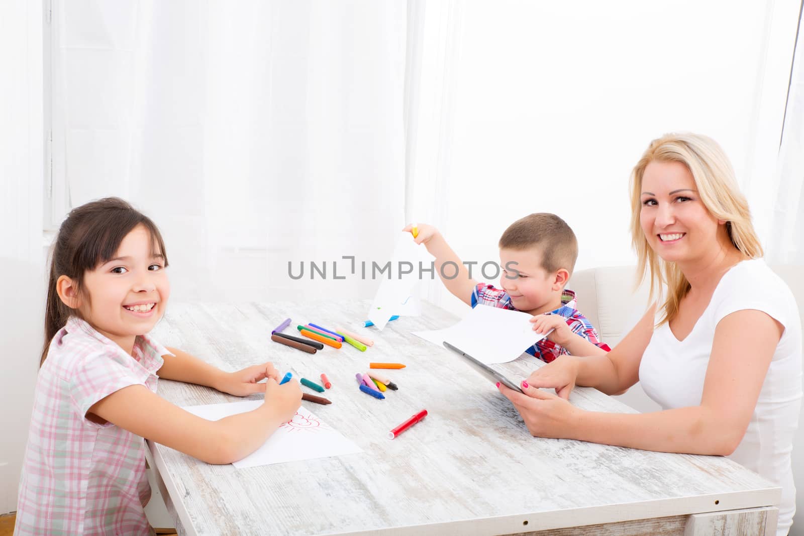 Mother and daughter and son at home at the table.
