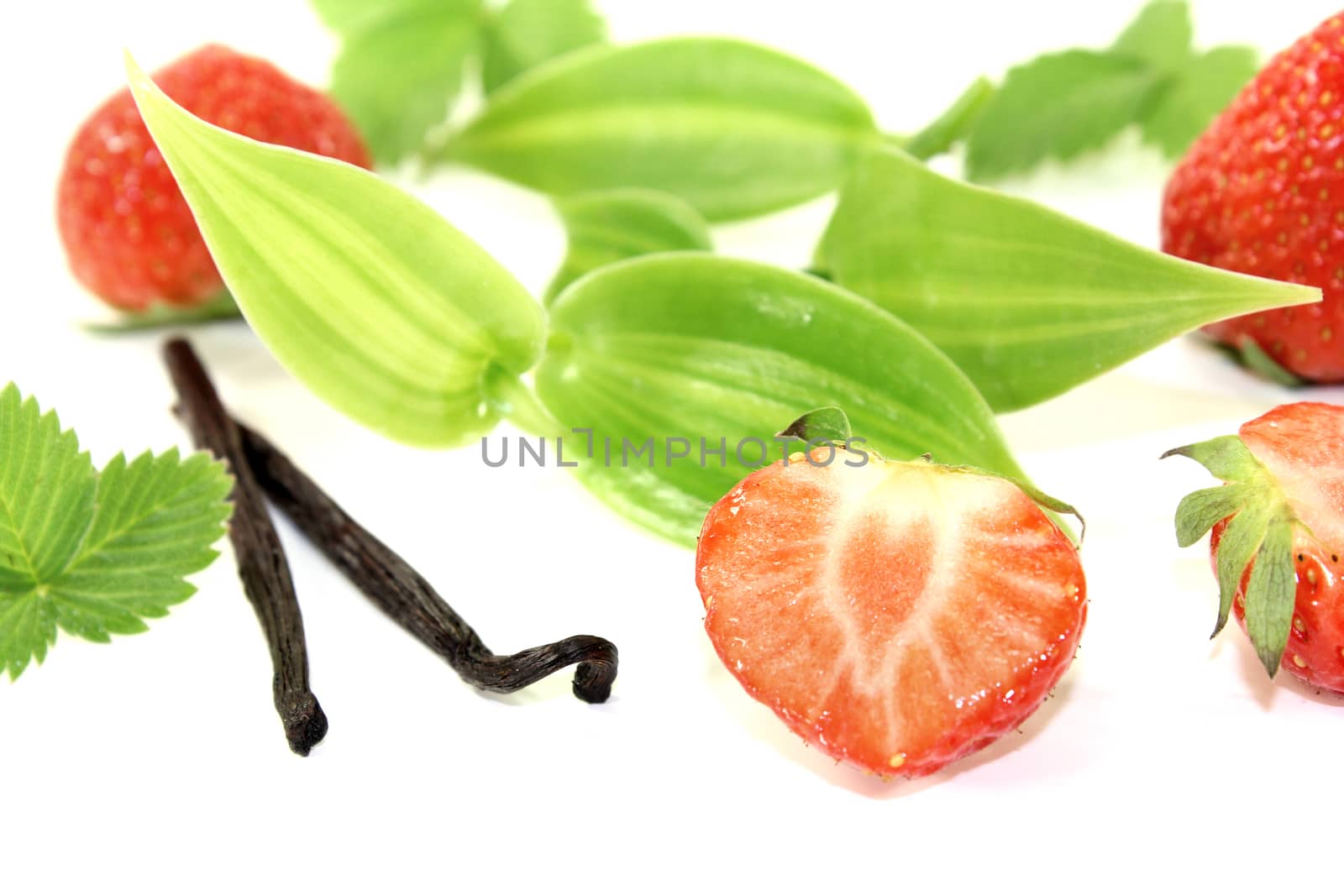 Vanilla leaves with juicy strawberries on a light background