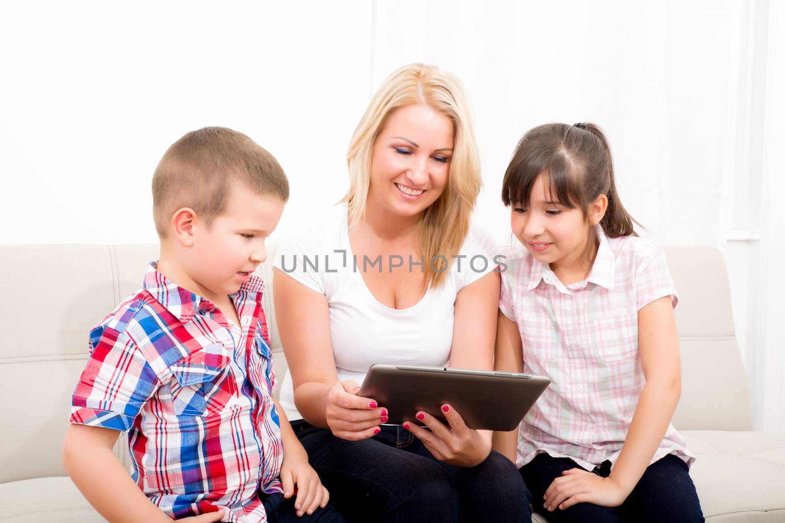 A mother using with her son and daughter a Tablet PC.
