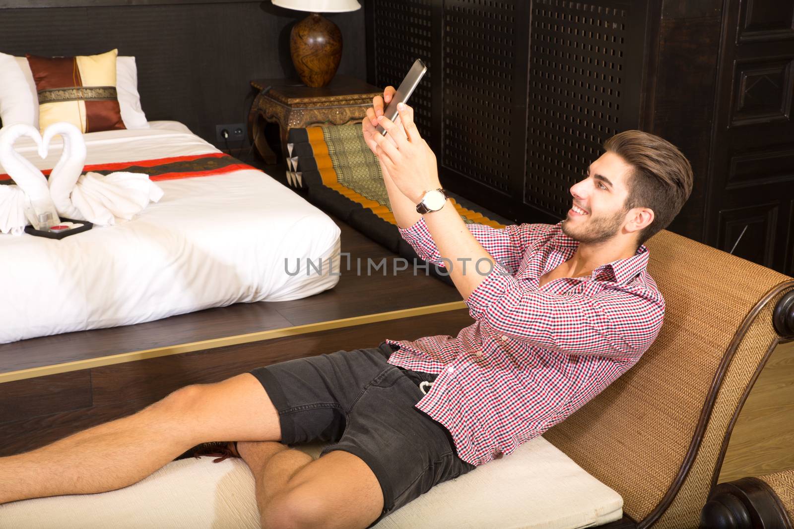 Young man in a hotel room taking a selfie		 by Spectral