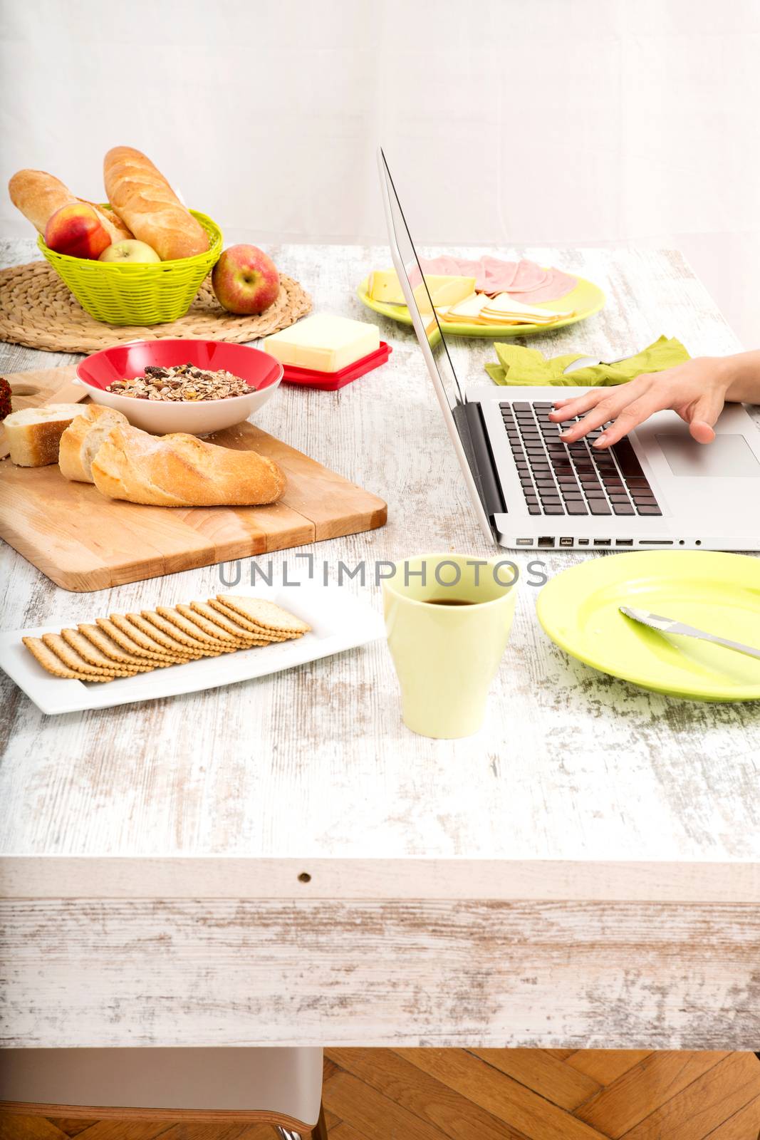 Young woman having breakfast while using a laptop computer by Spectral