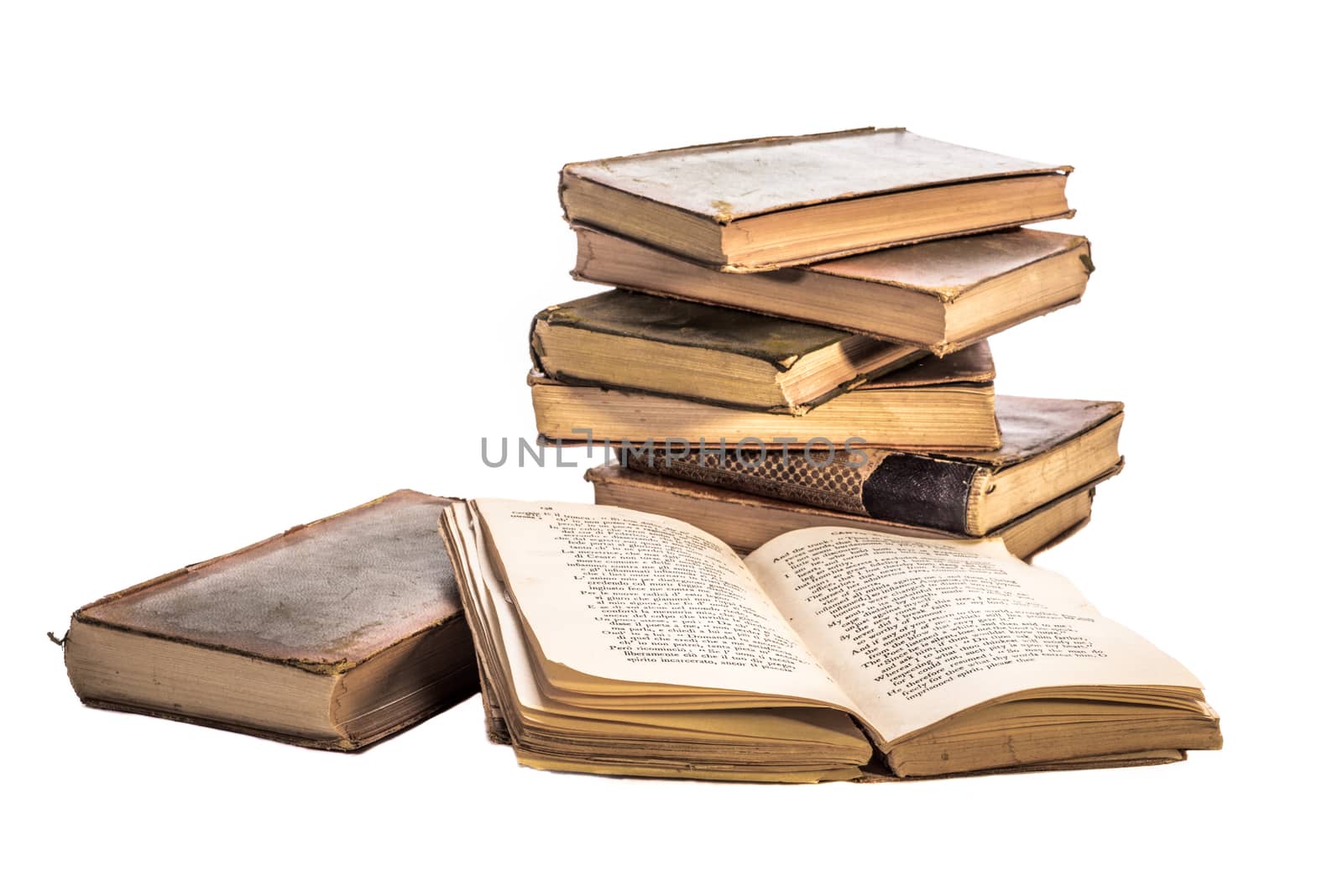 Old and much neglected books stacked one on top of the other, with one book lying open infront of the stack. Photographed on a white background