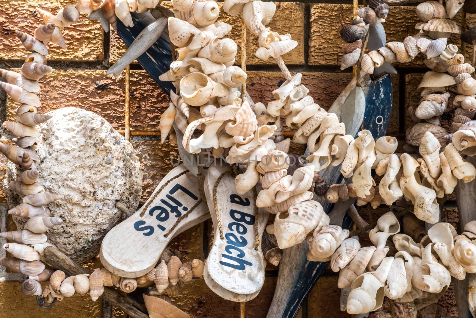 Outside wall decoration at a beach house with a variety of found objects as well as crafted objects, all creating a beach and sea and ocean theme.