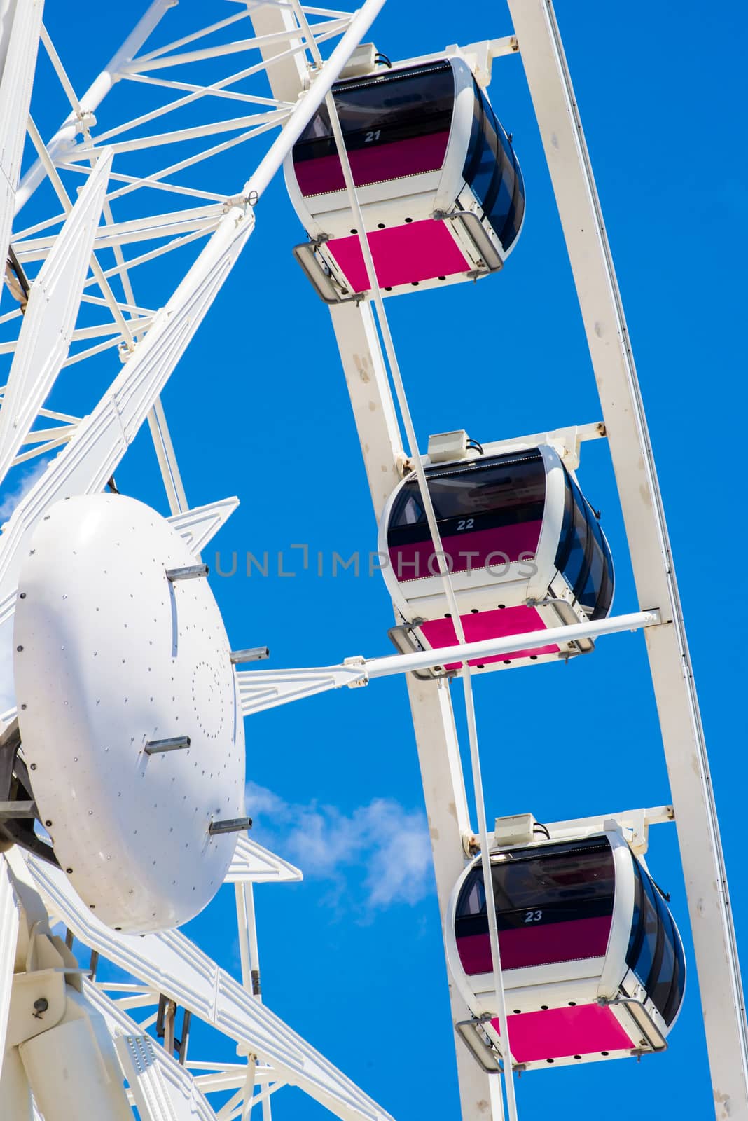 Three pods of a ferris wheel high up in the blue sky with an amazing view of the land below.