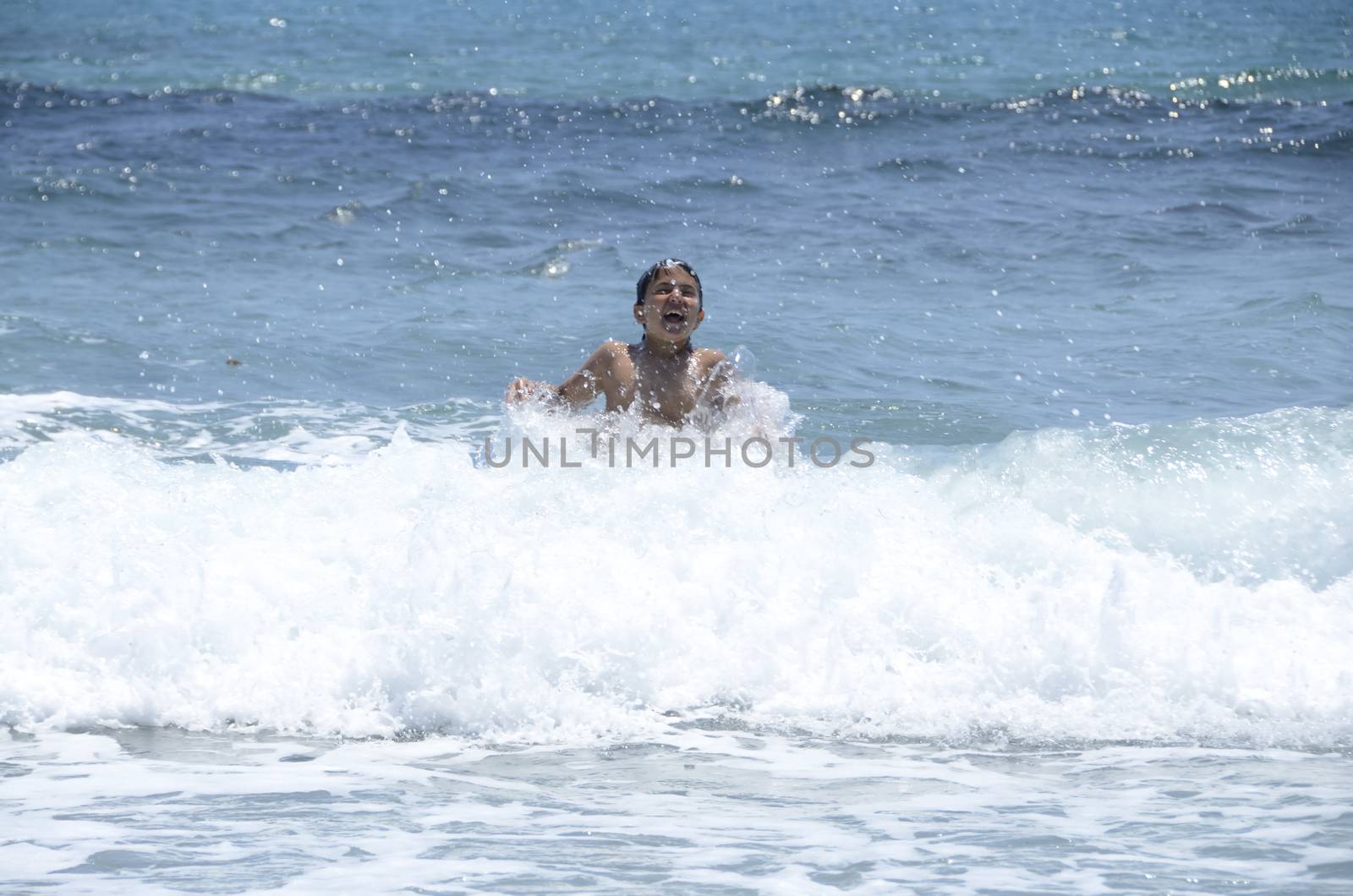 Happy summer for the child at the beach with the waves and splashing water.