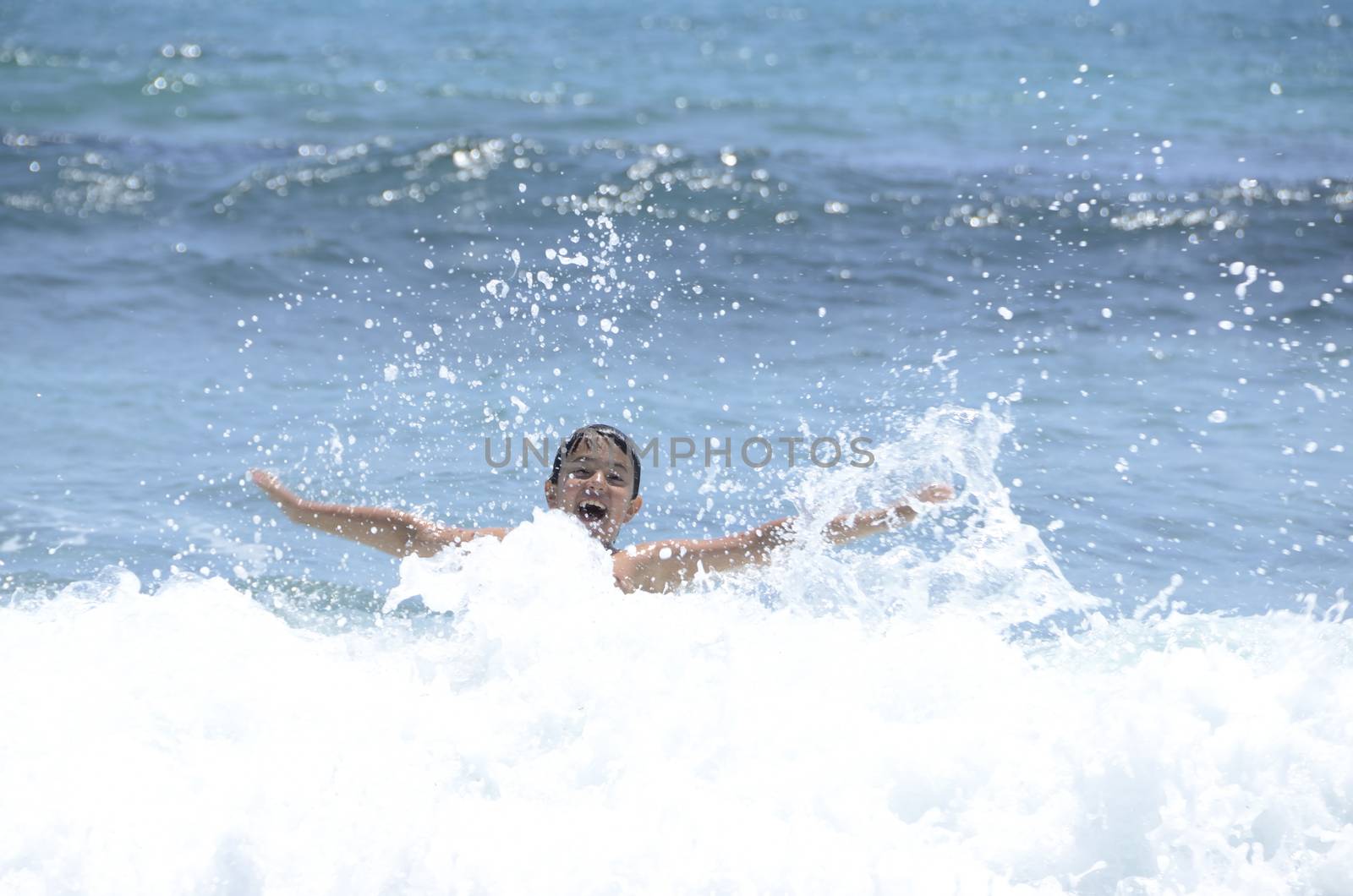 Happy summer for the child at the beach with the waves and splashing water.